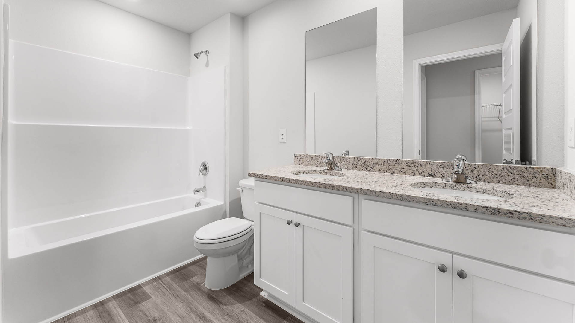 Bathroom with double vanity granite countertops and toilet and combined shower and tub.