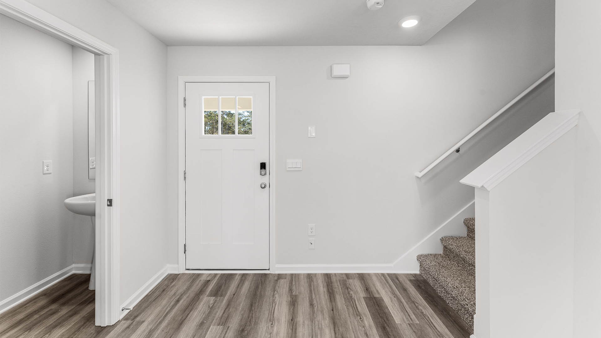 Front door next to staircase and half-bathroom.