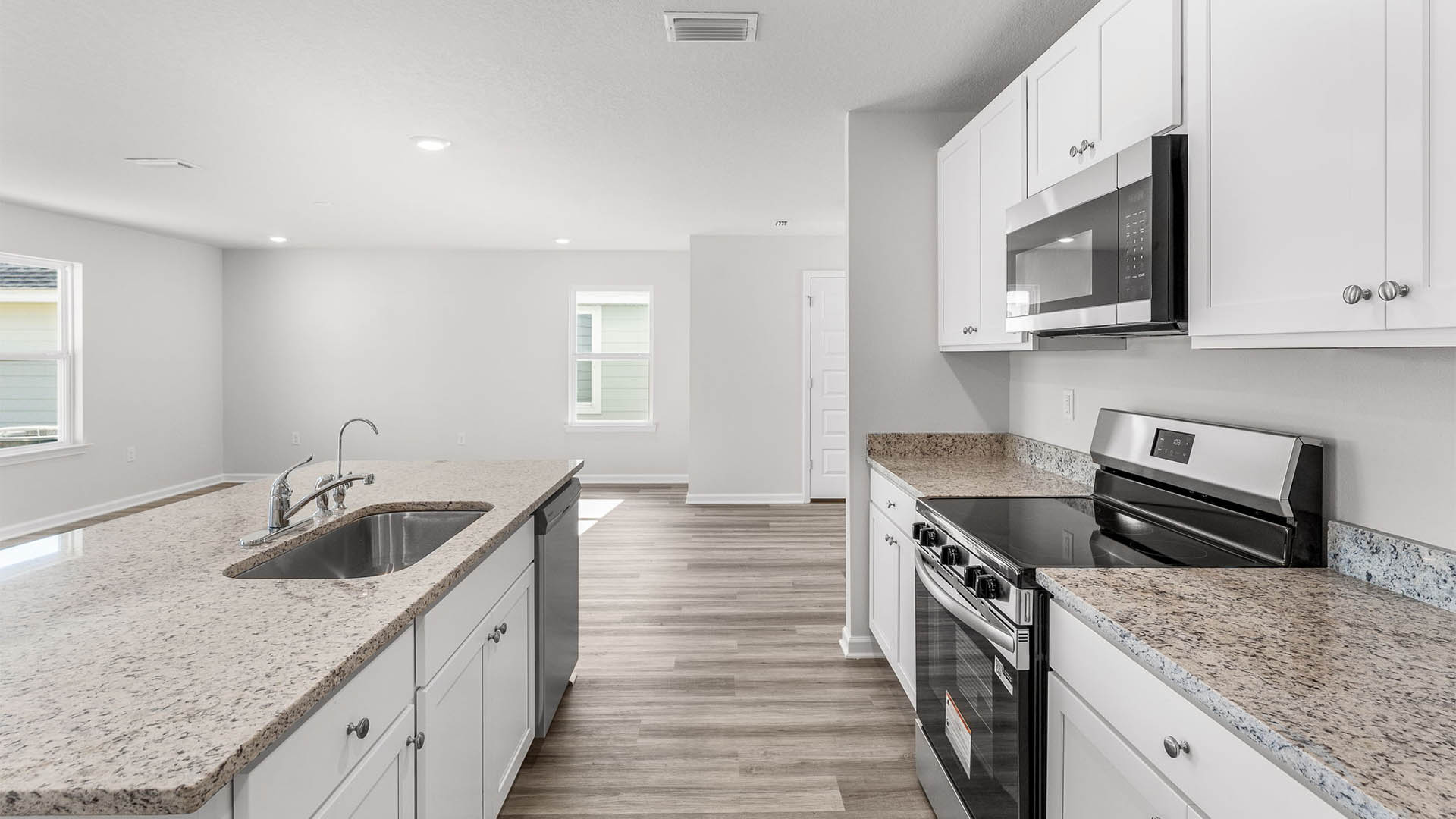 Kitchen with island and granite countertops and white cabinetry and stainless-steel appliances.