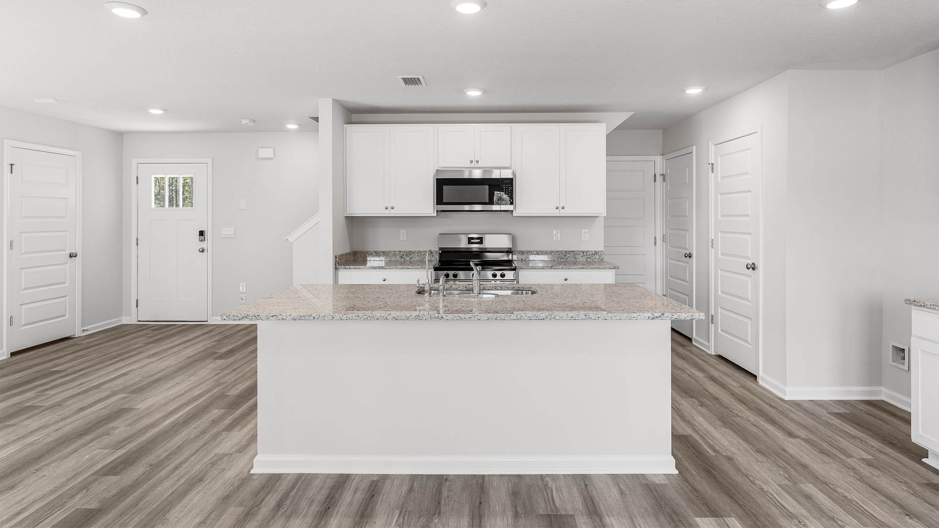 Kitchen with island and granite countertops and white cabinetry and stainless-steel appliances.