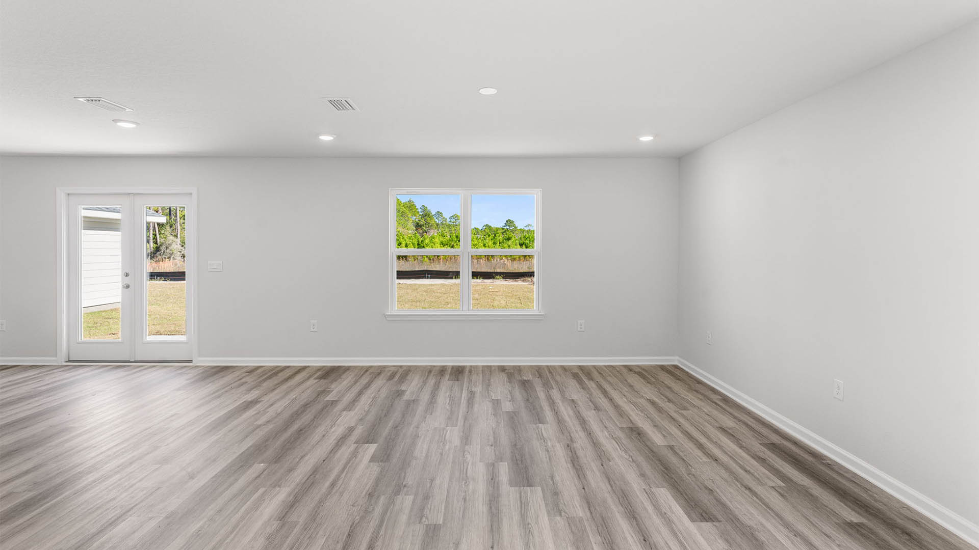Living room with EVP flooring and windows and back door.