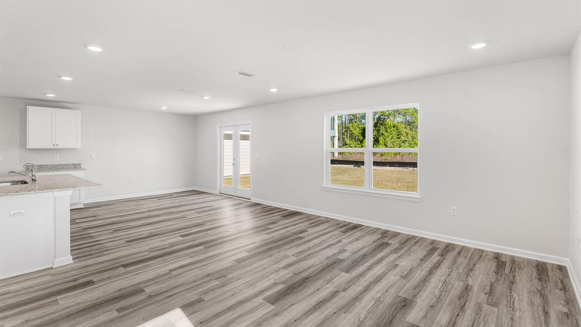 Living room with EVP flooring and windows and back door.