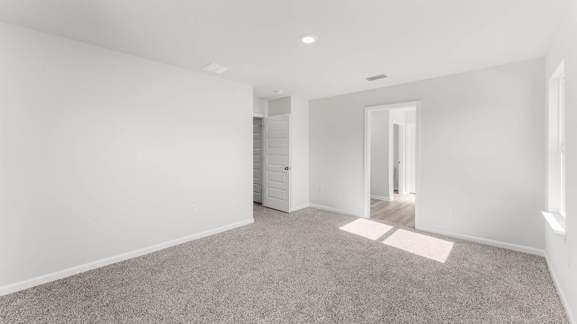 Primary bedroom with carpet floor and bathroom entrance.