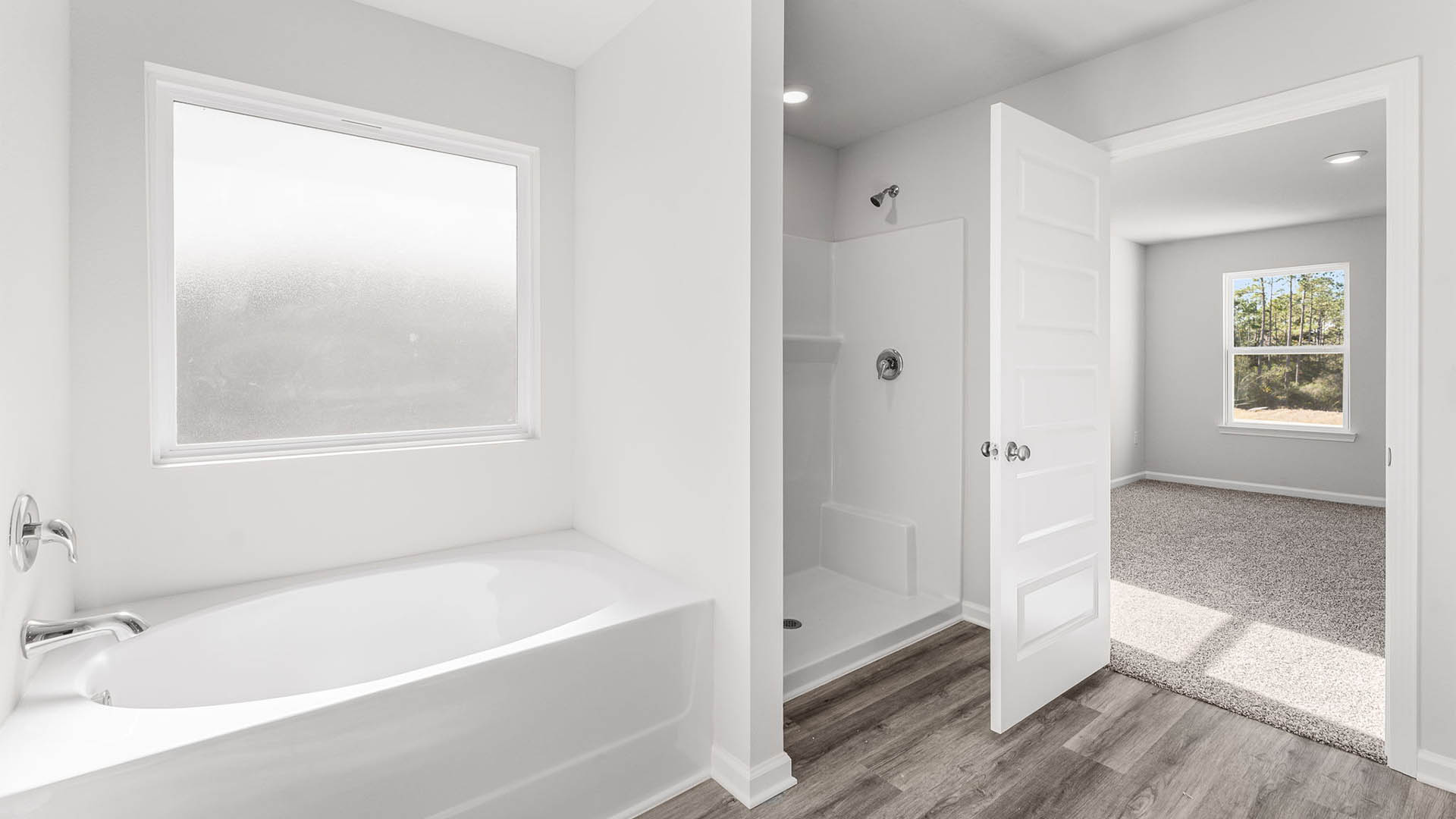 Primary bathroom with separate shower and tub with coated window.