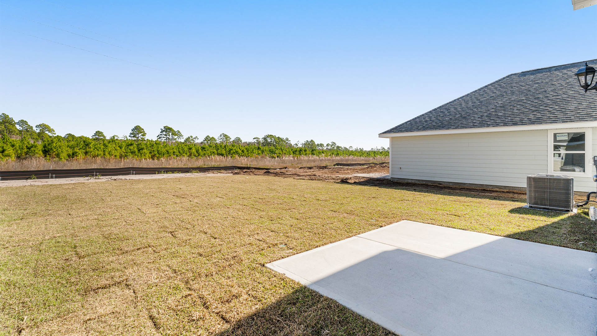 Back yard view and concrete pad on rear of home.