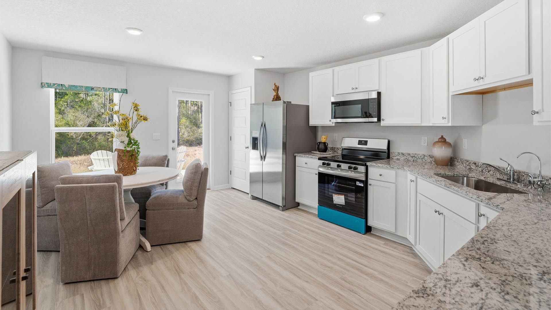 Kitchen with granite countertops and stainless-steel appliances and white cabinets and back door and dining area.