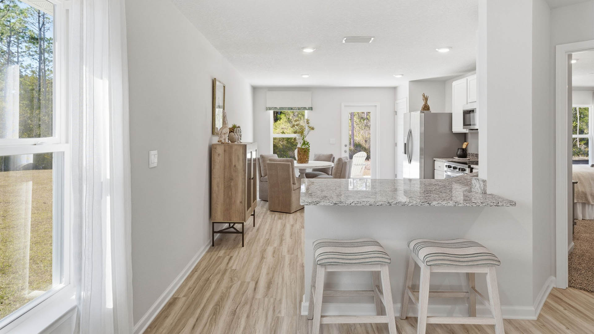 Kitchen with granite countertops and stainless-steel appliances and white cabinets and back door and dining area.