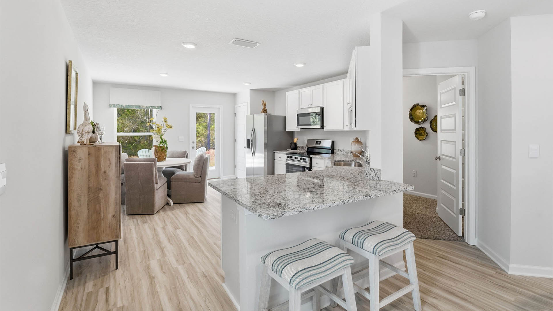 Kitchen with granite countertops and stainless-steel appliances and white cabinets and back door and dining area.