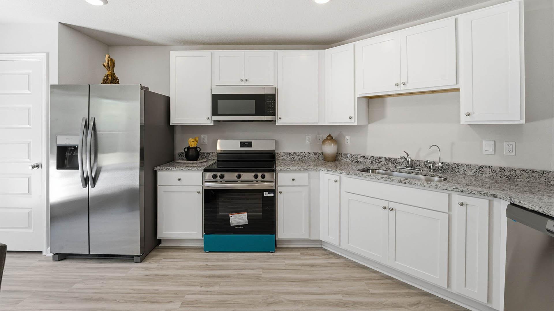 Kitchen with granite countertops and stainless-steel appliances and white cabinets.