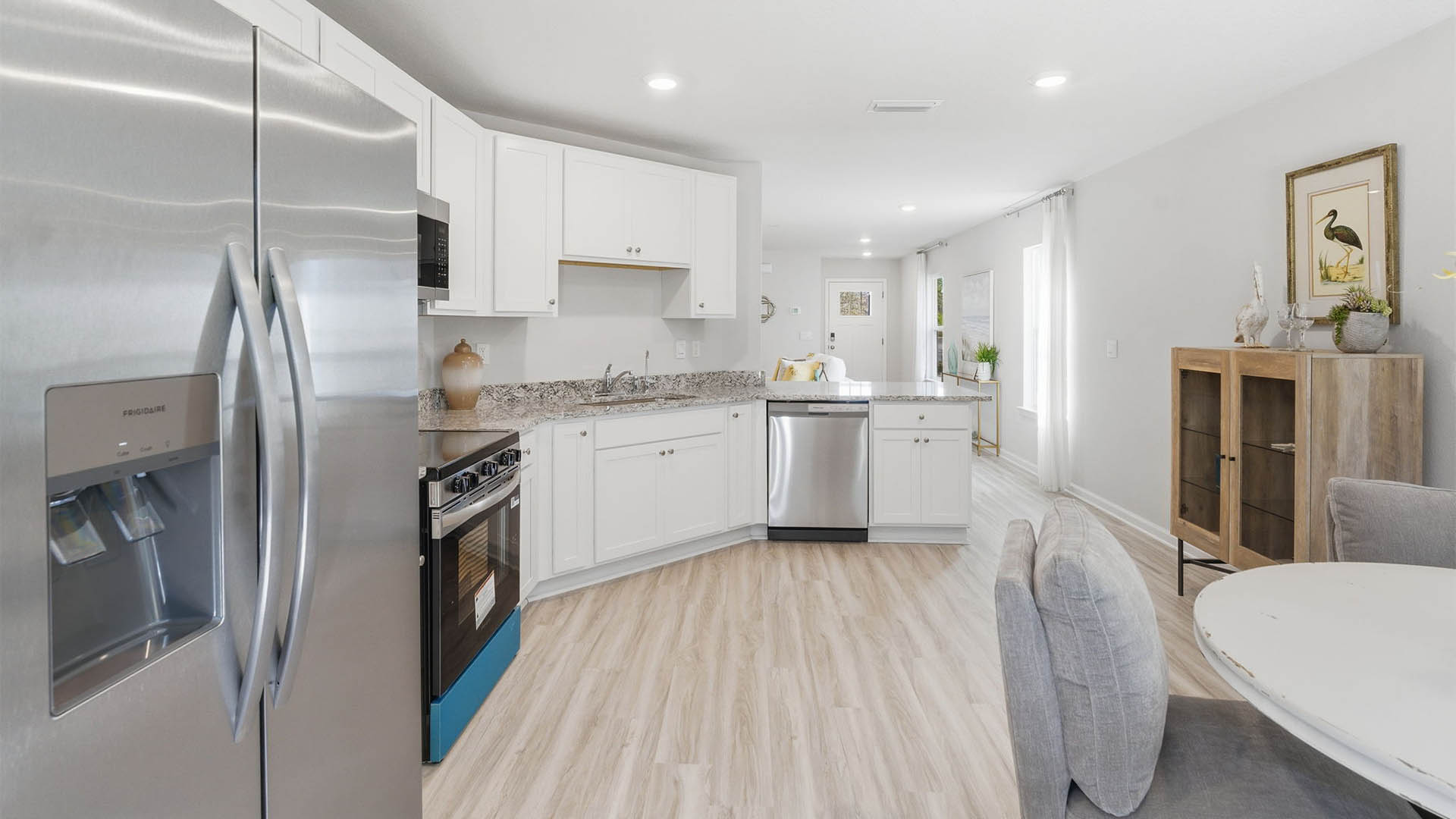 Kitchen with granite countertops and stainless-steel appliances and white cabinets.
