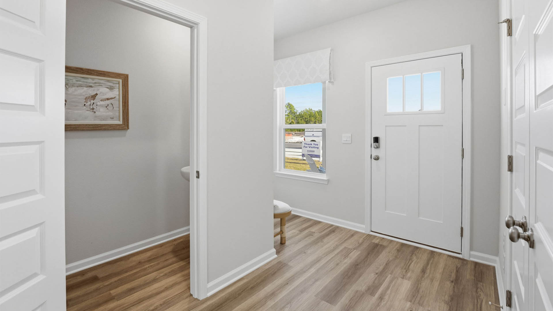 Front entrance with EVP flooring next to half-bathroom and closet.