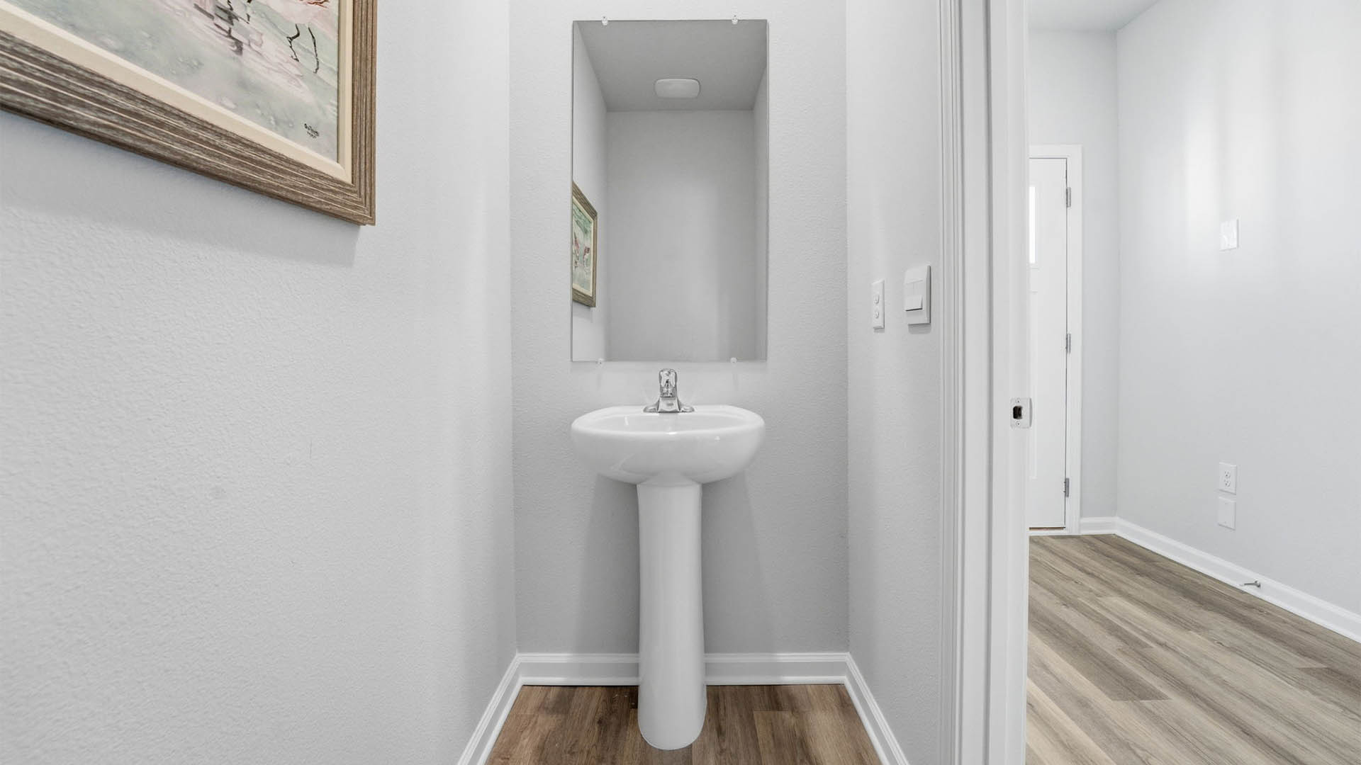Half-bathroom with EVP flooring and sink and mirror next to front door.