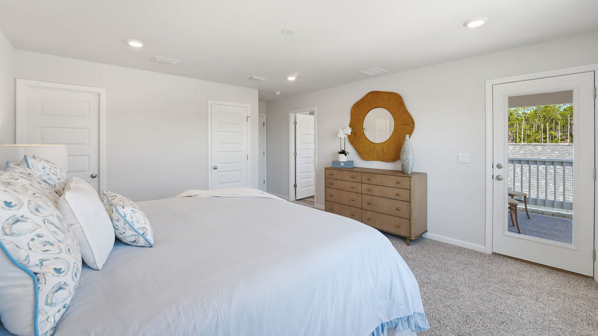 Primary bedroom with carpet floors and window and bathroom entrance and closet and balcony door.