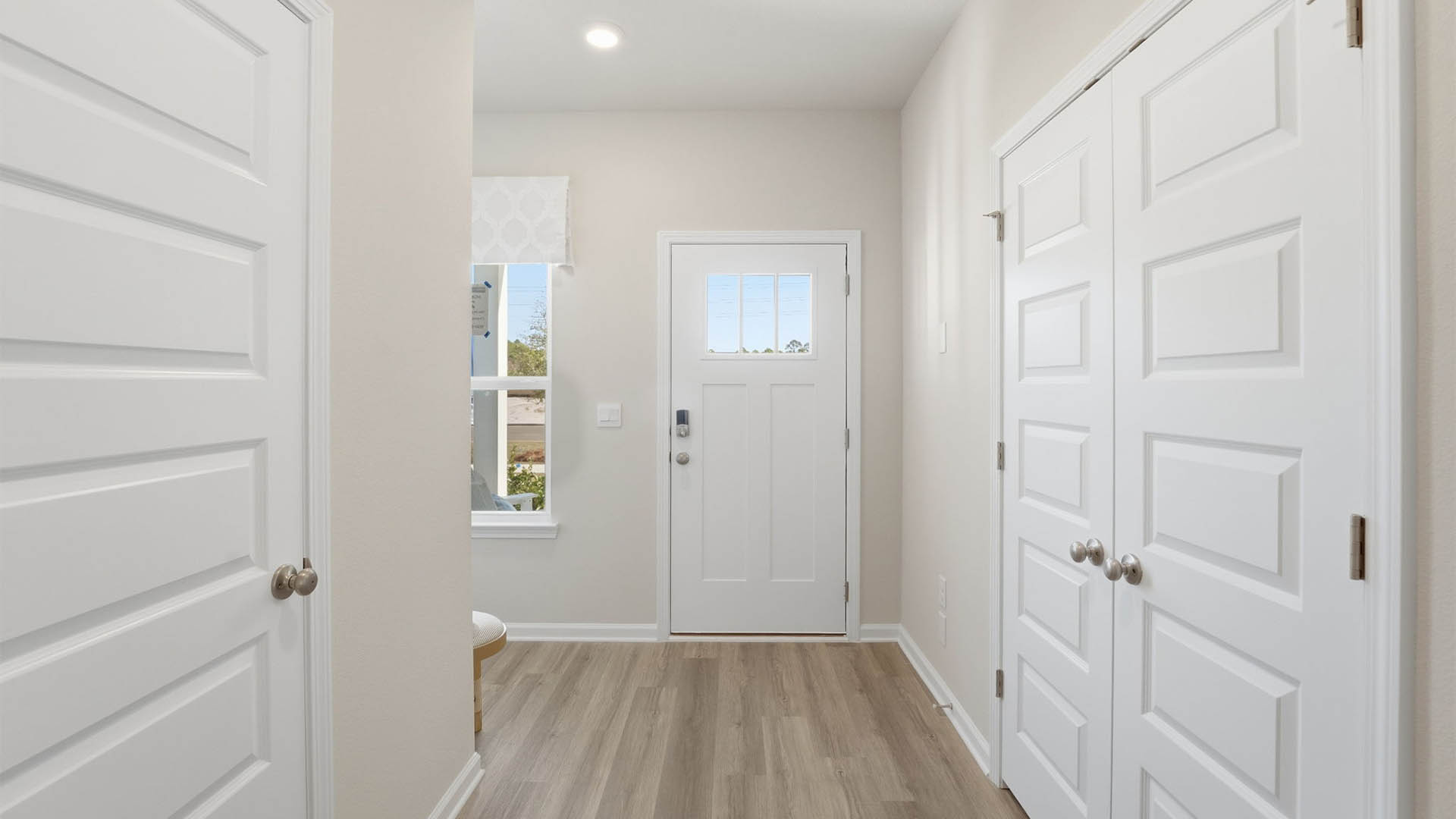 Front entrance with EVP flooring next to half-bathroom and closet.
