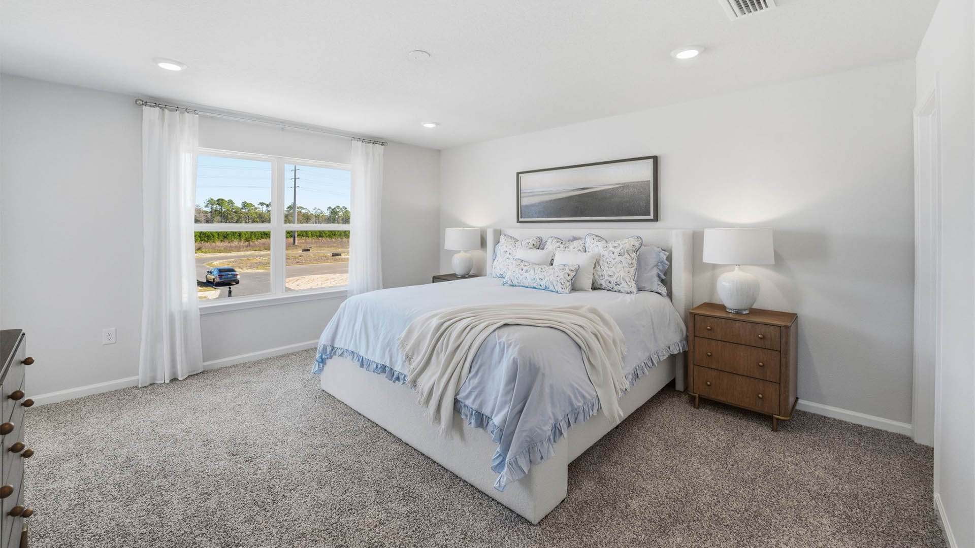 Primary bedroom with carpet floors and window and bathroom entrance.