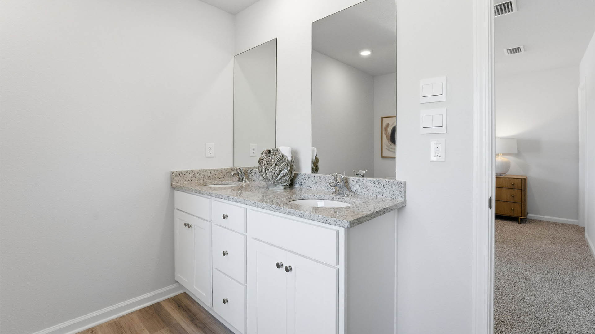 Primary bathroom with double vanity sinks with granite countertops.