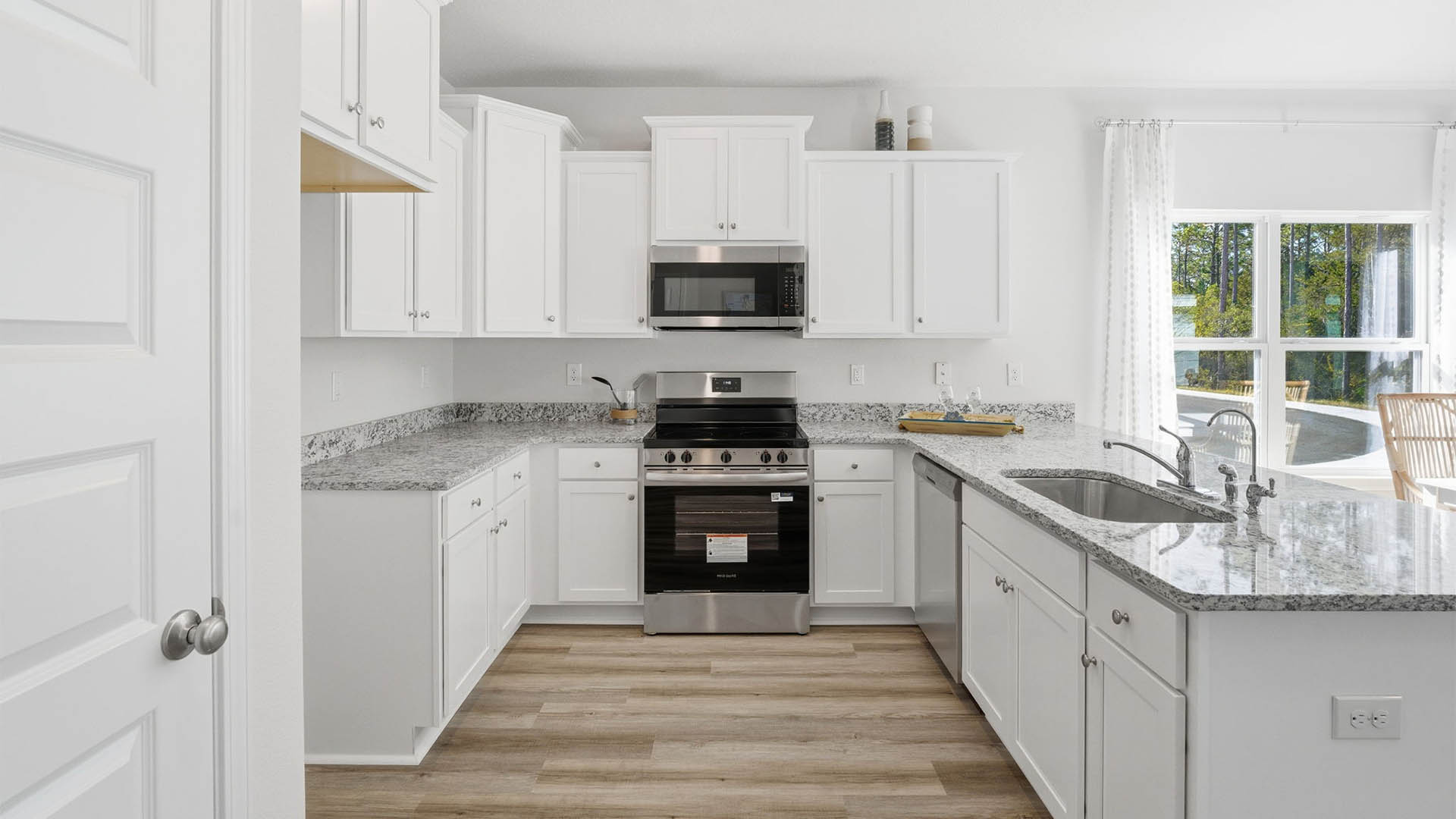 Kitchen with white cabinets and granite countertops and stainless-steel appliances and peninsula bar and pantry.