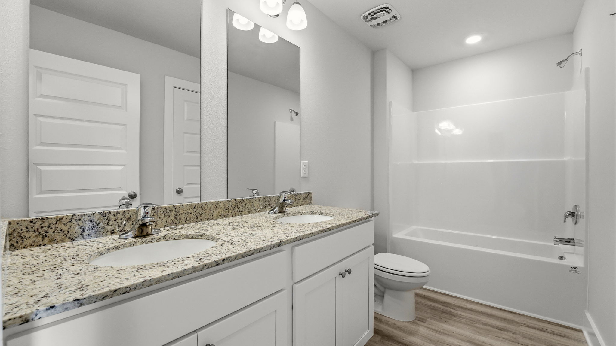 Bathroom with granite countertops and double vanity and shower and tub and toilet.