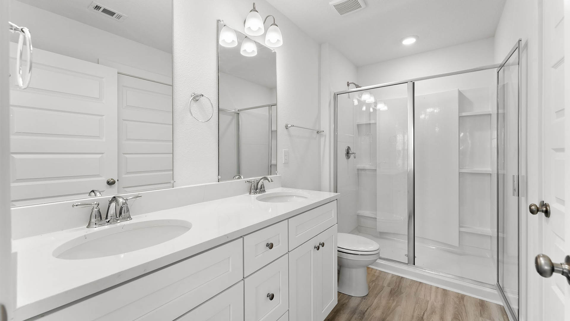 Primary bathroom with white quartz countertops and shower with glass door and toilet.