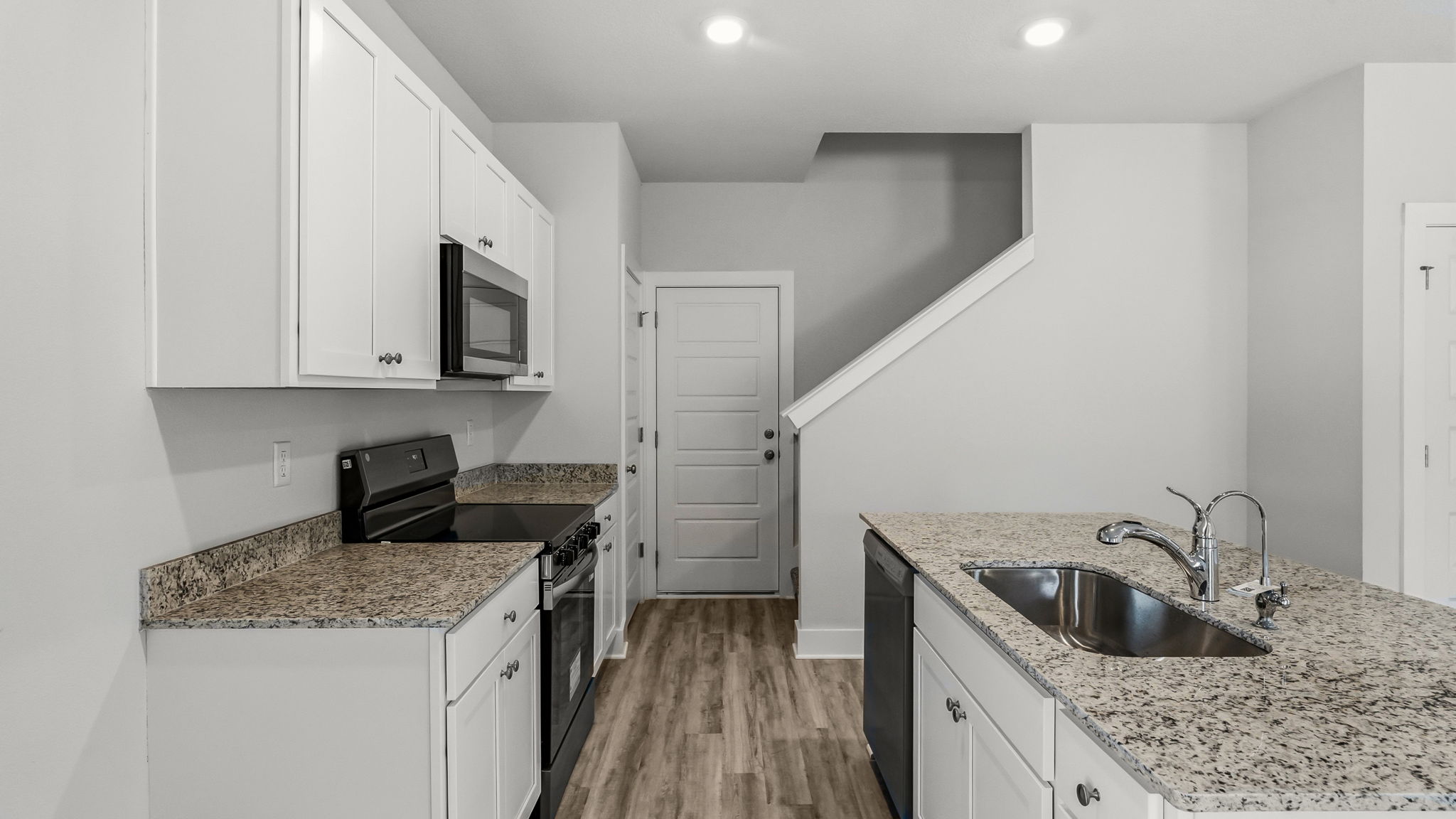 Kitchen with stainless-steel appliances and white cabinets and granite countertops and island.