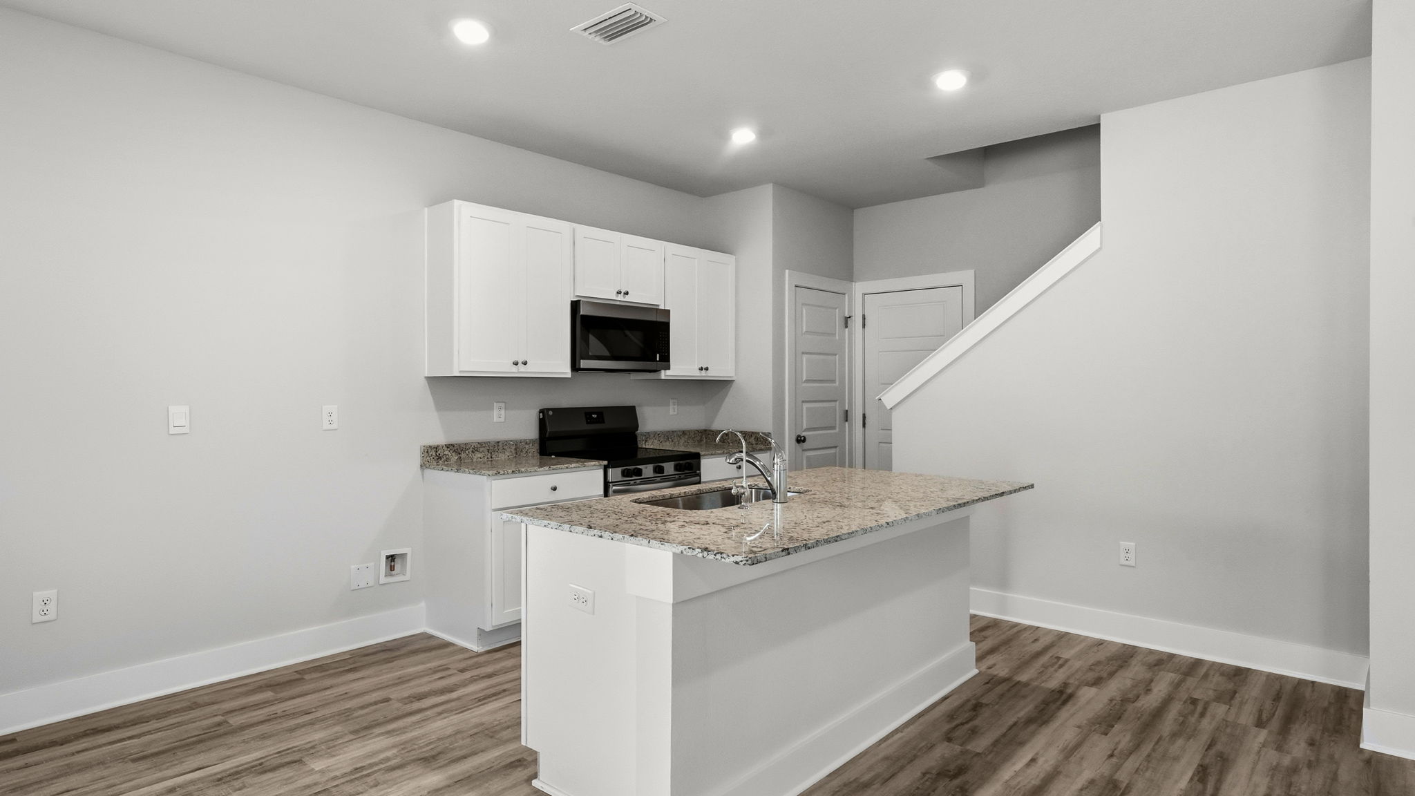 Kitchen with stainless-steel appliances and white cabinets and granite countertops and island.