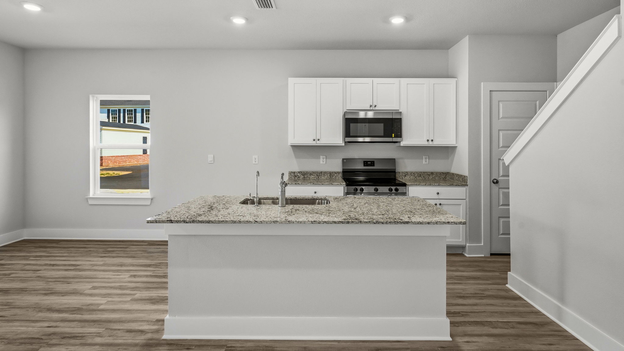 Kitchen with stainless-steel appliances and white cabinets and granite countertops and island.