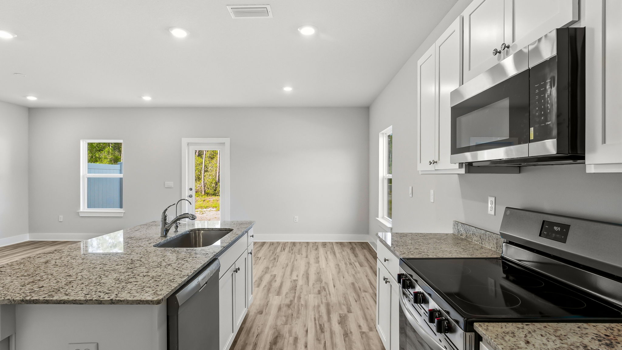 Kitchen with stainless-steel appliances and white cabinets and granite countertops and island.
