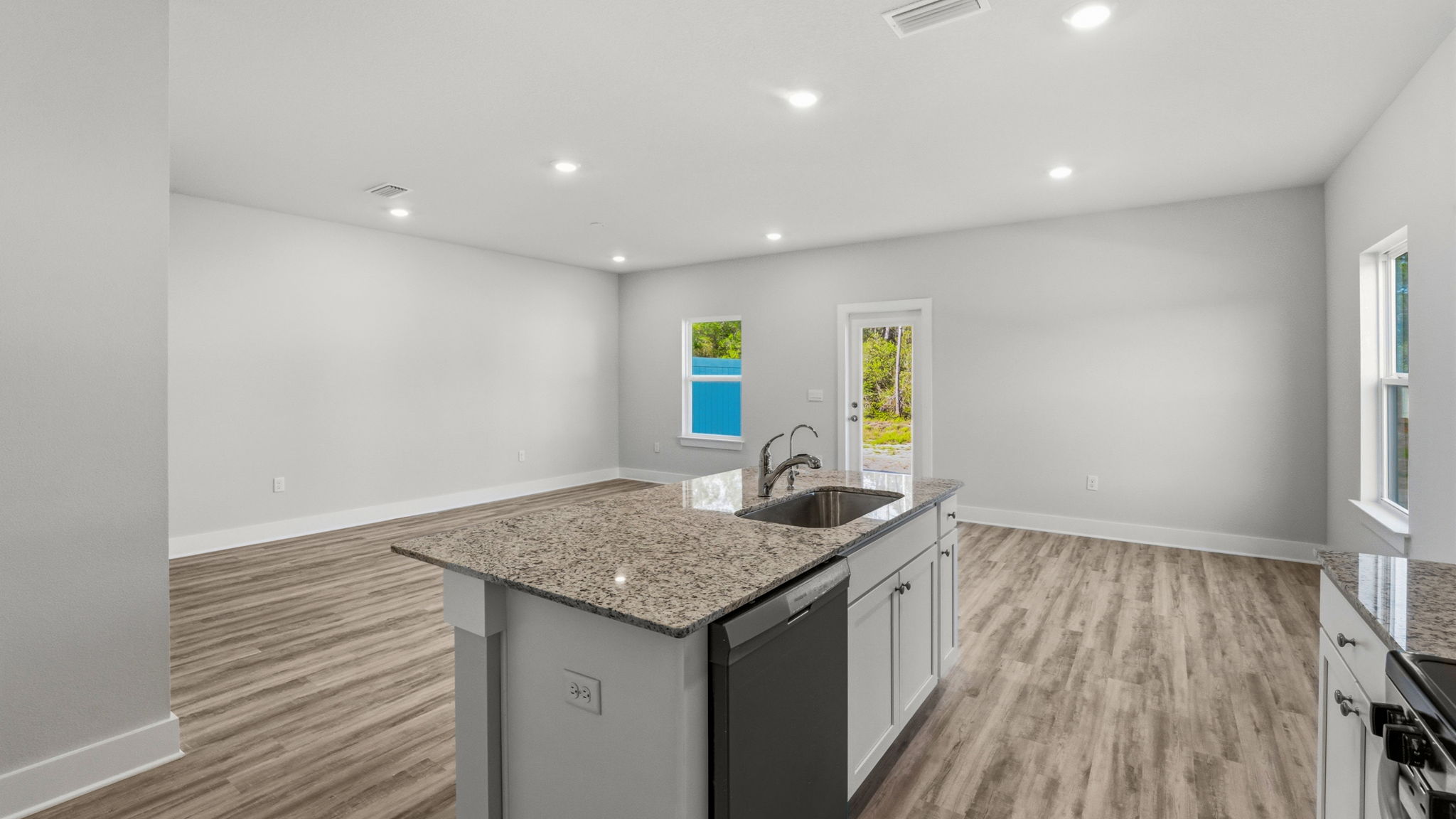 Kitchen with stainless-steel appliances and white cabinets and granite countertops and island.