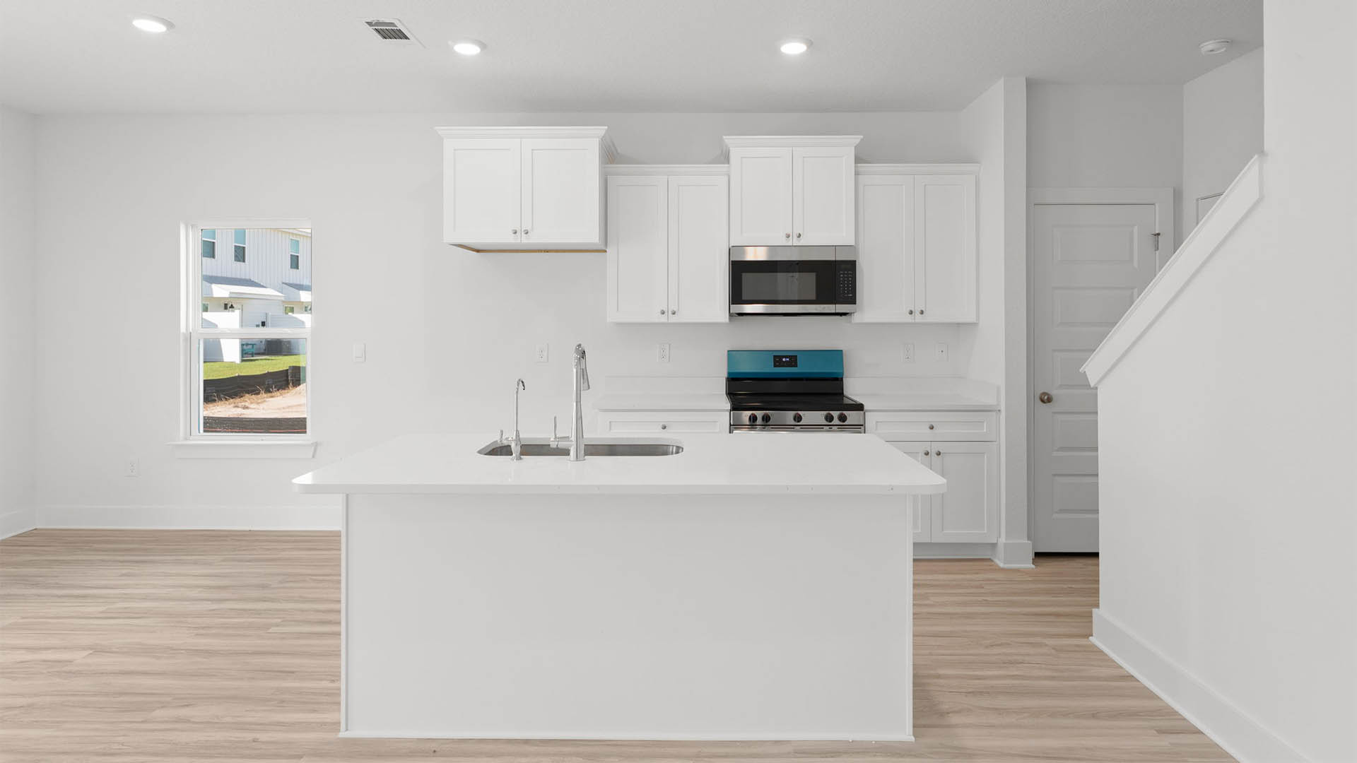 Kitchen with stainless-steel appliances and white cabinets and quartz countertops and island.