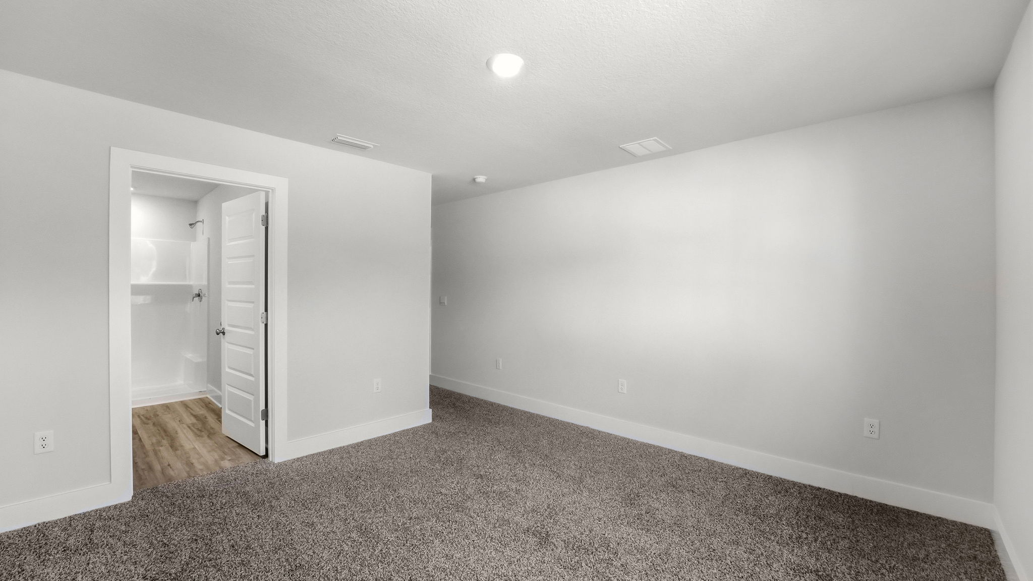 Primary bedroom with carpet flooring and bathroom entrance.