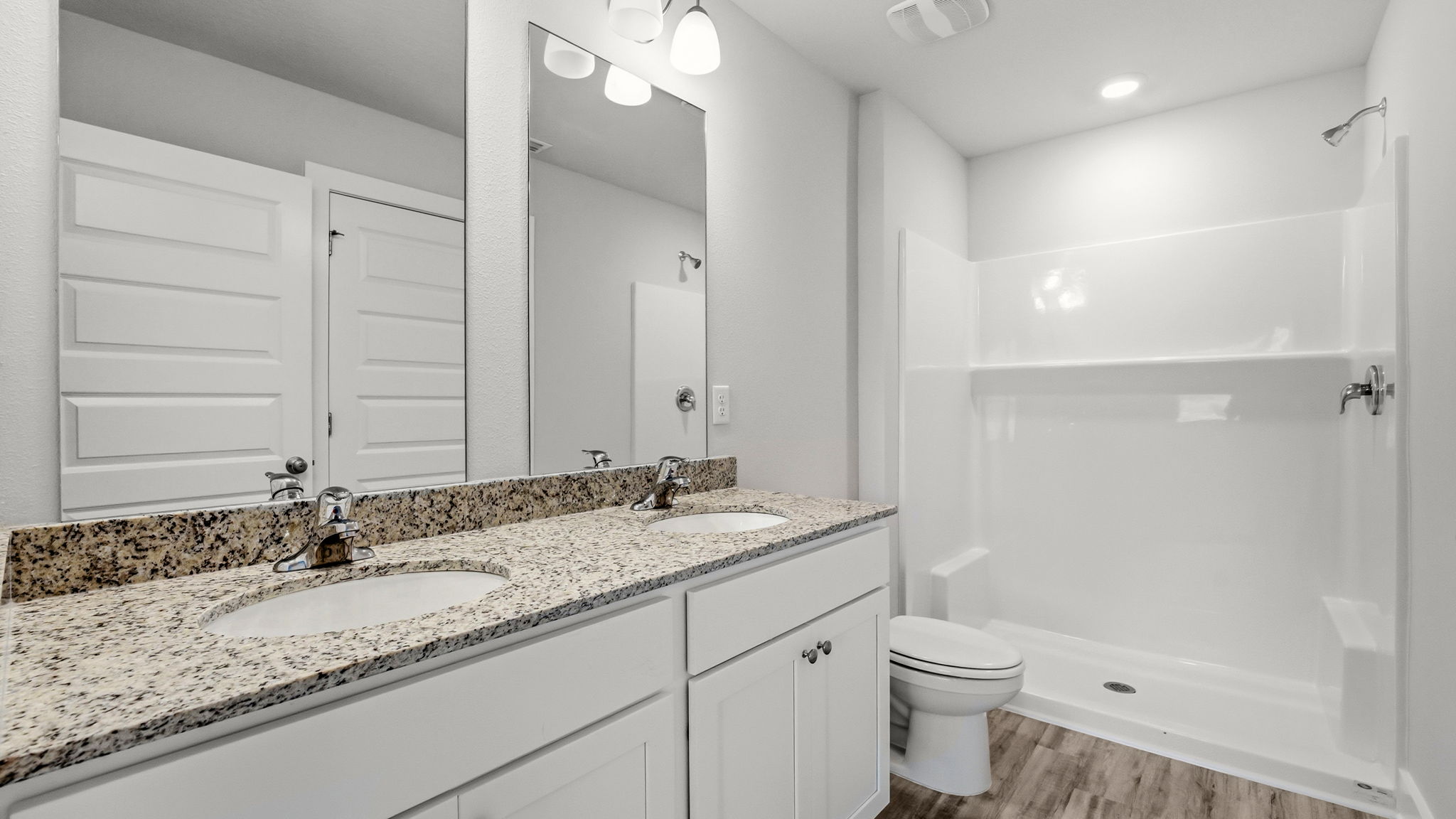 Bathroom with granite countertops and double vanity and shower and toilet.