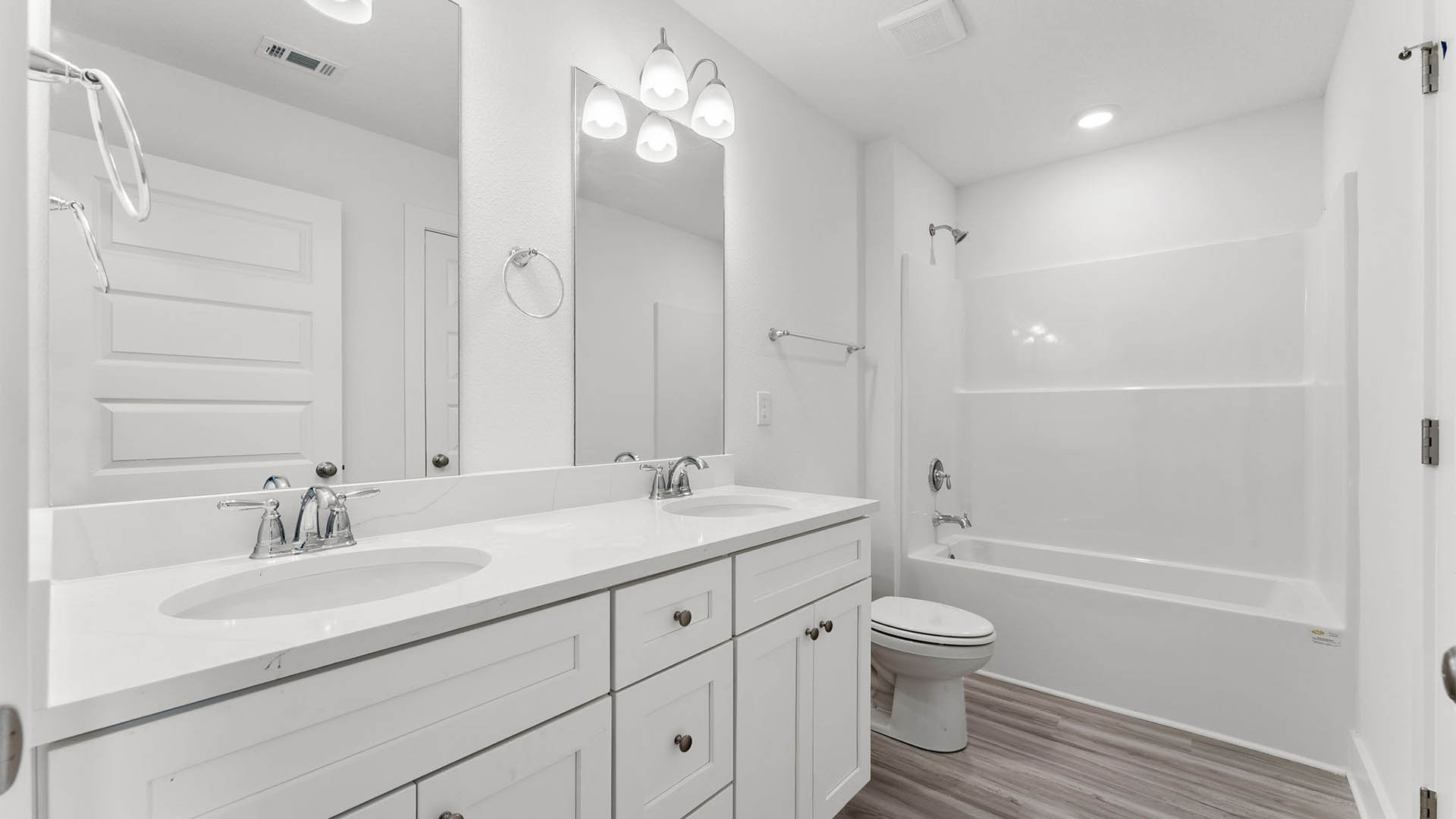 Bathroom with white quartz countertops and shower with glass door and toilet.
