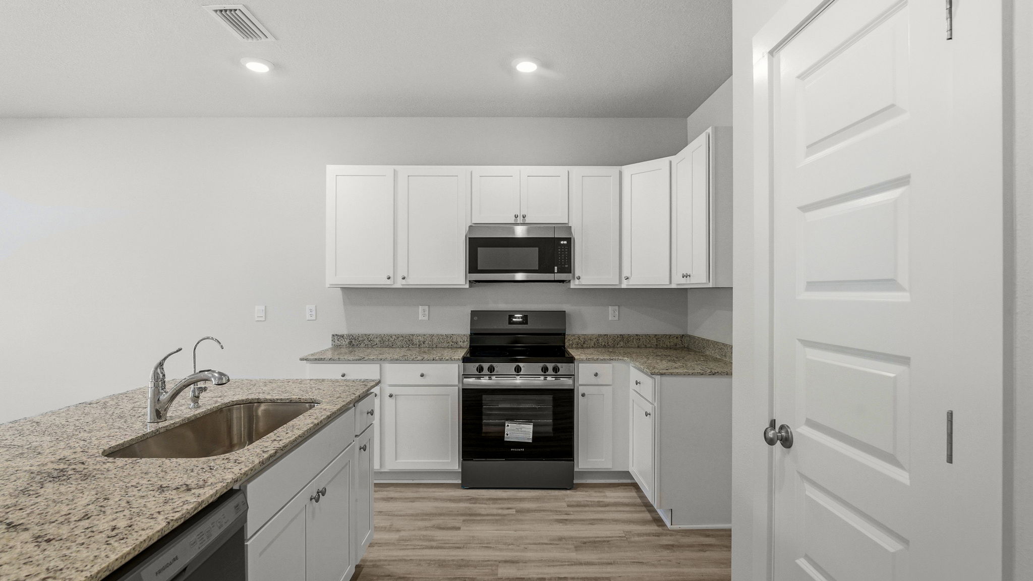 Kitchen with granite countertops and stainless-steel appliances and island and white cabinets.