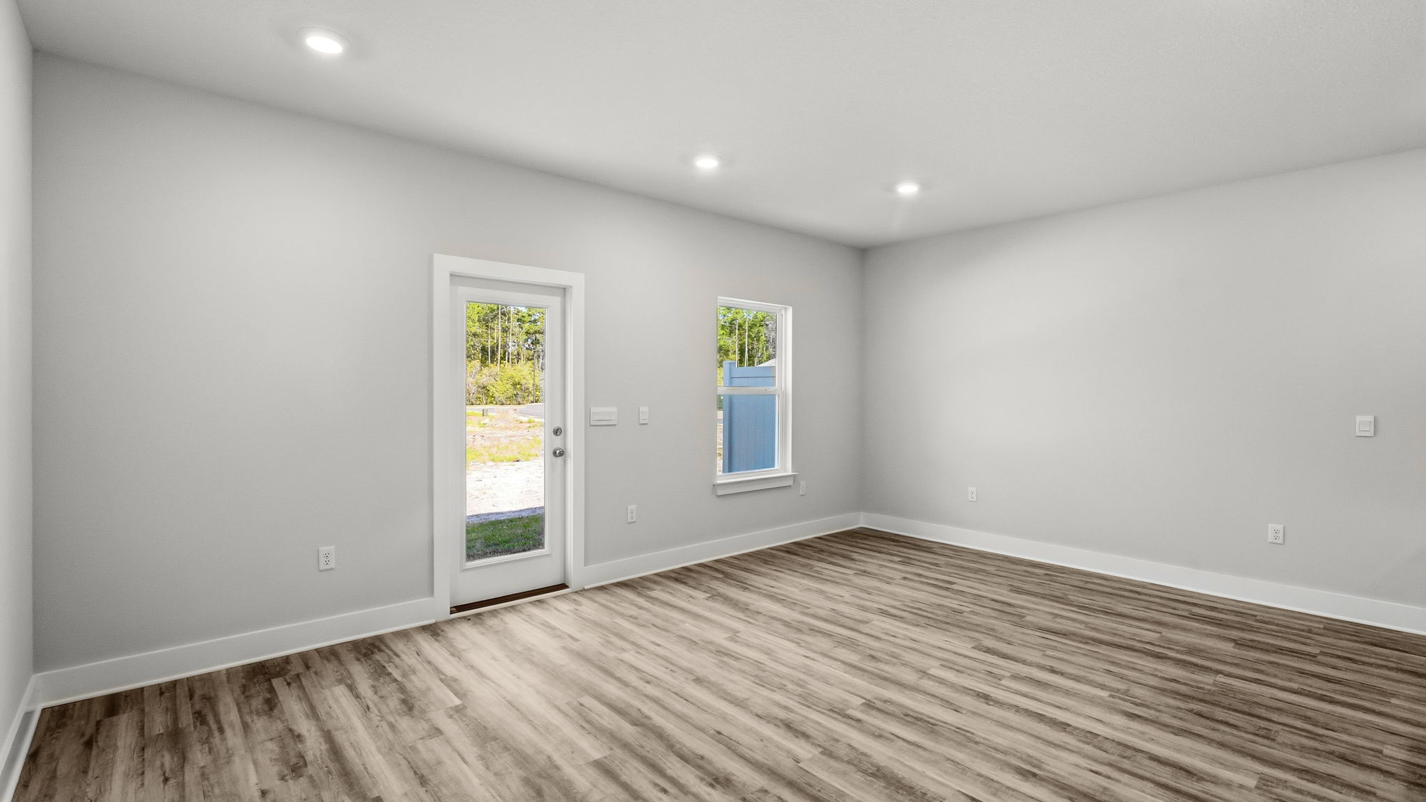 Open living room with EVP flooring and back door and window.