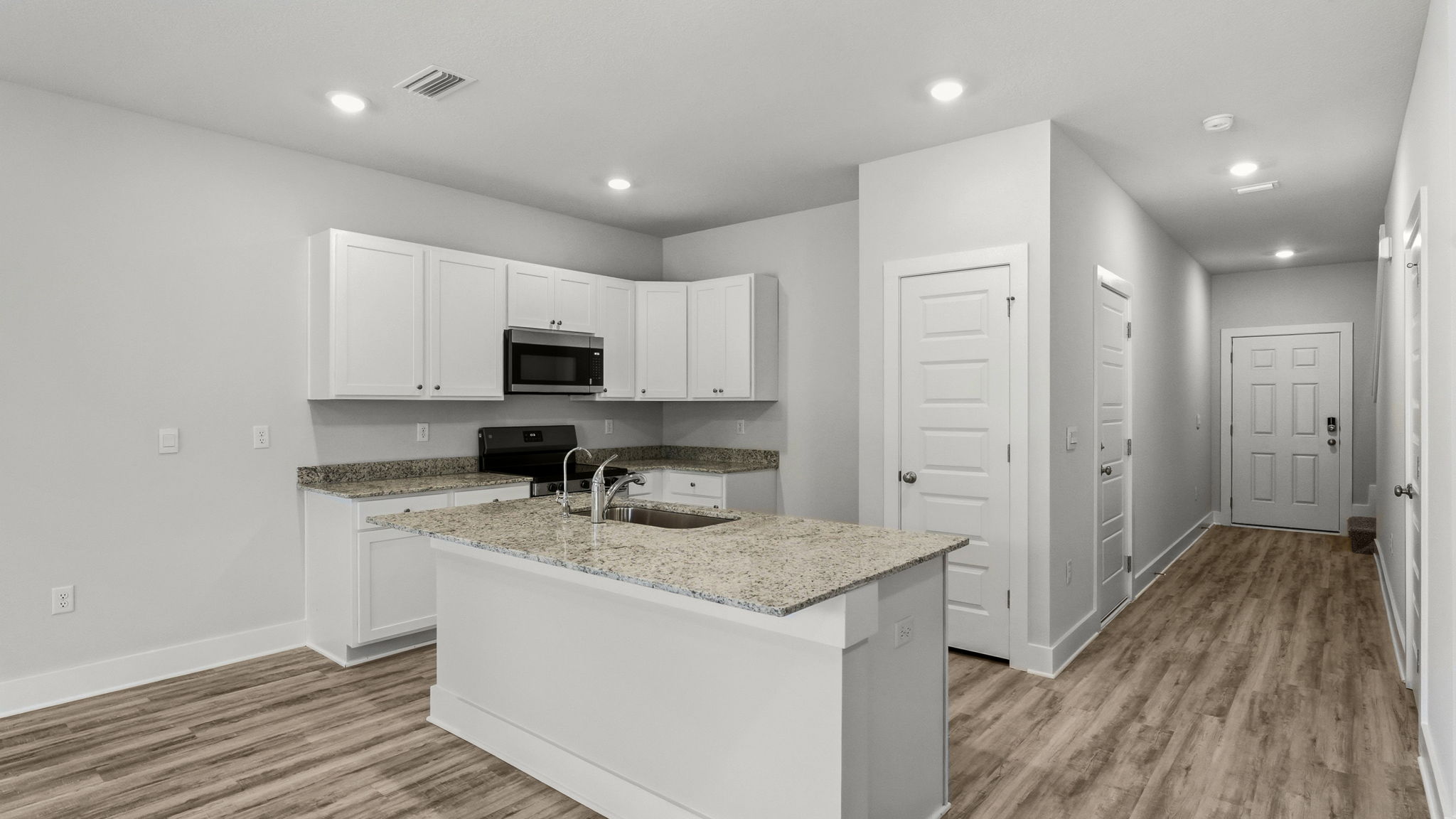 Kitchen with granite countertops and stainless-steel appliances and island and white cabinets.