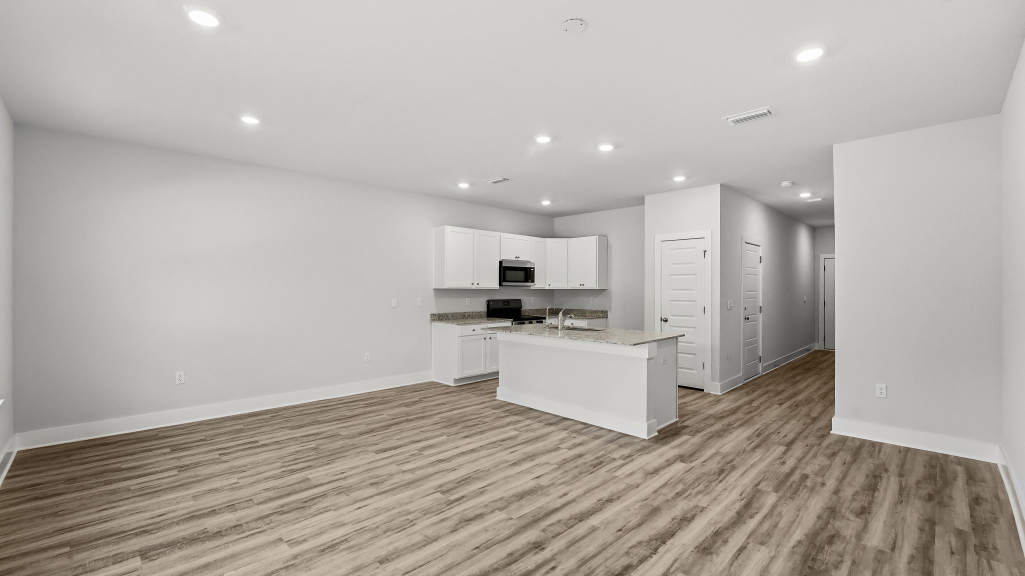 Open living room with EVP flooring and kitchen.