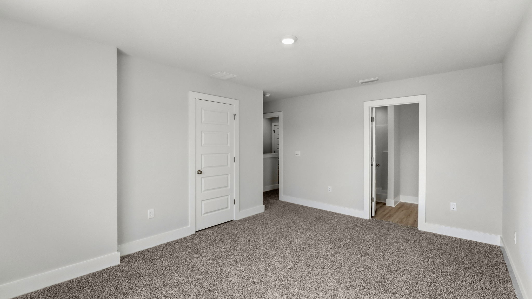 Primary bedroom with carpet flooring and closet and bathroom entrance.