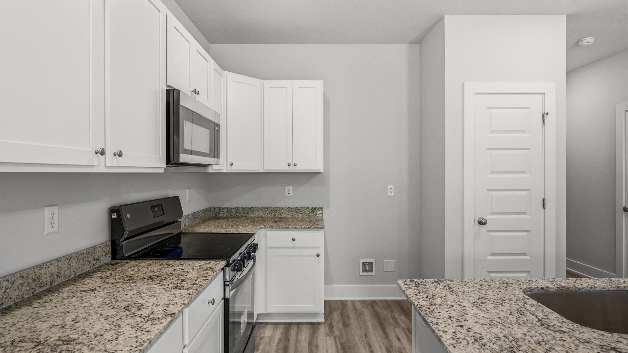 Kitchen with granite countertops and stainless-steel appliances and island and white cabinets.