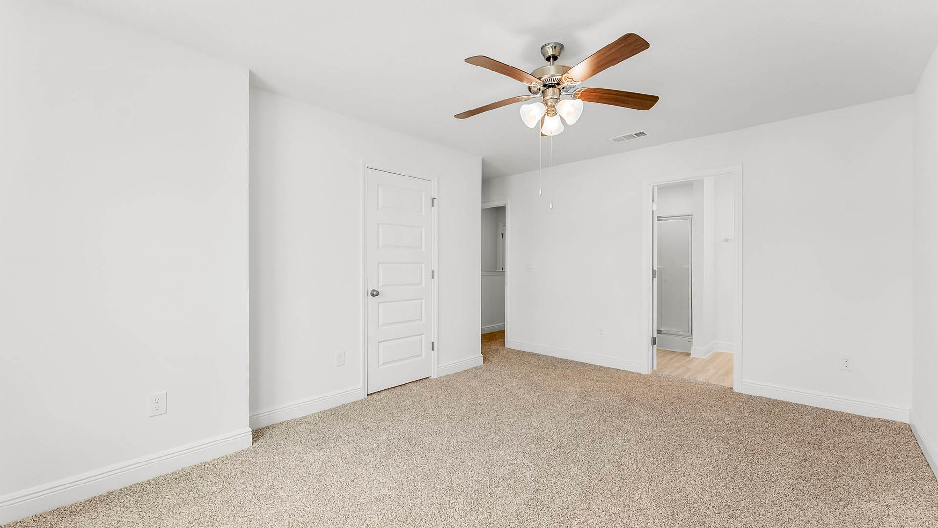 Primary bedroom with ceiling fan and closet and bathroom entrance.