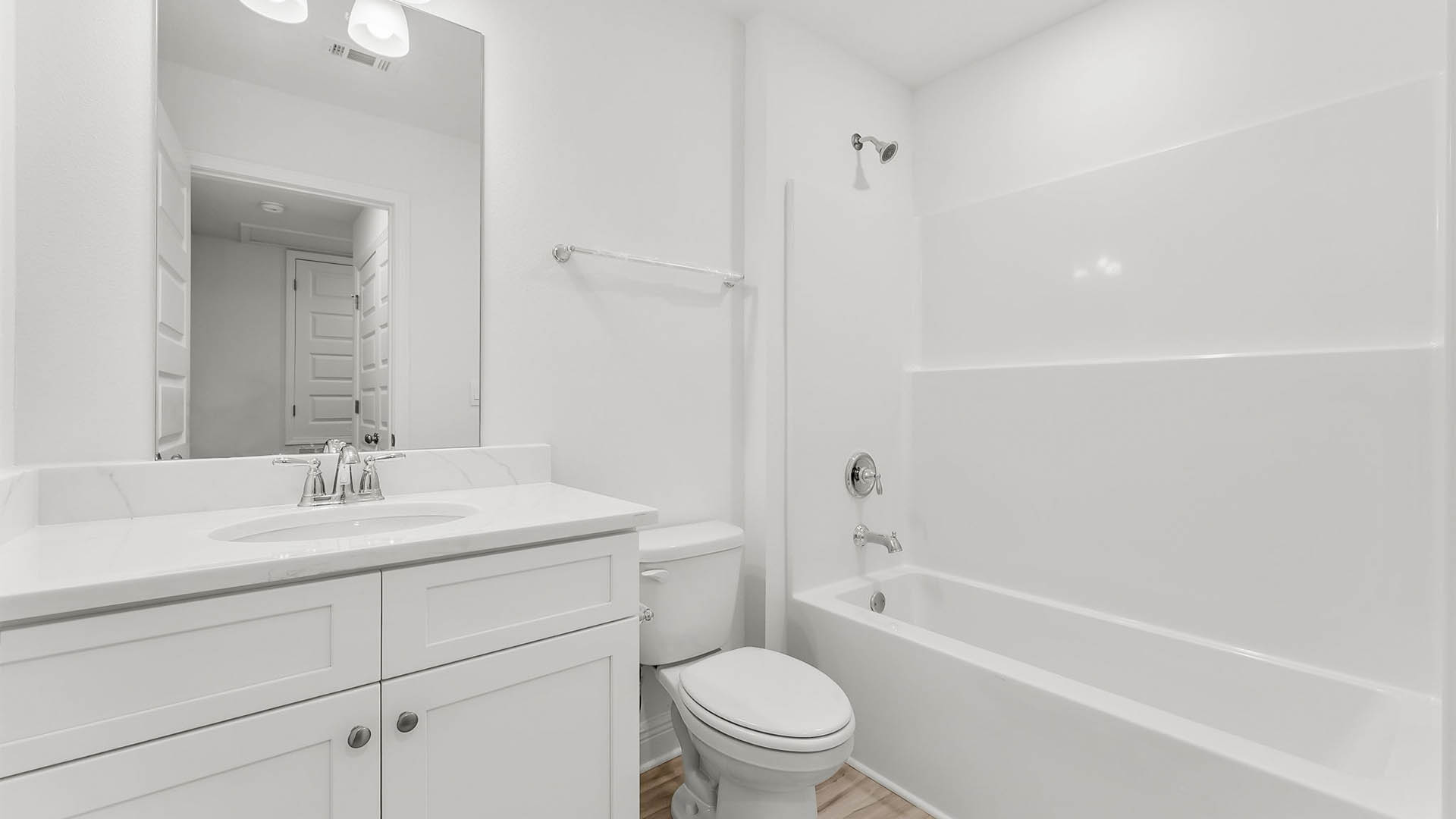Bathroom with single vanity and quartz countertop and white cabinets and shower and toilet.