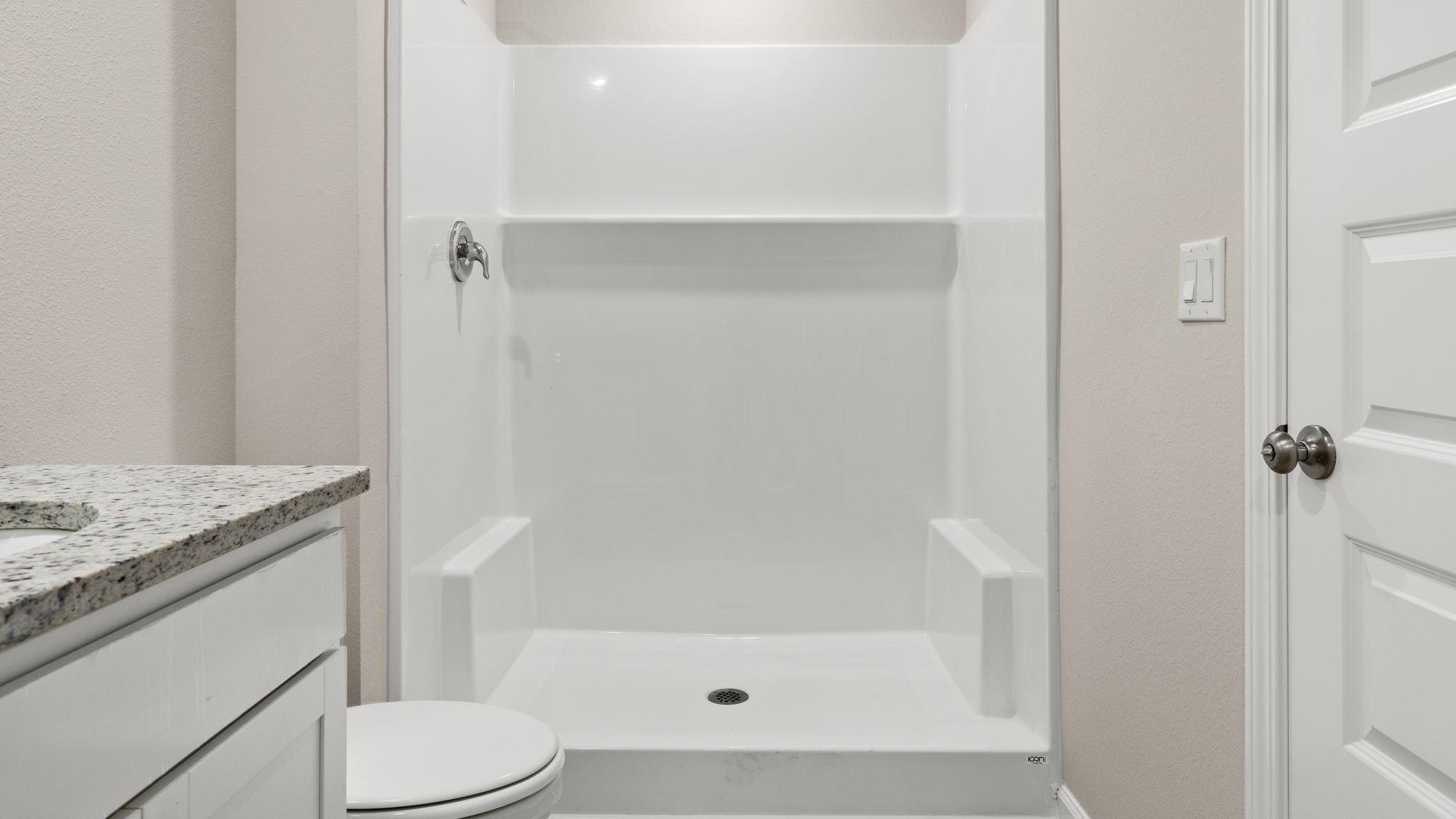 Bathroom with granite countertops and white cabinets and single vanity sinks and toilet and shower.