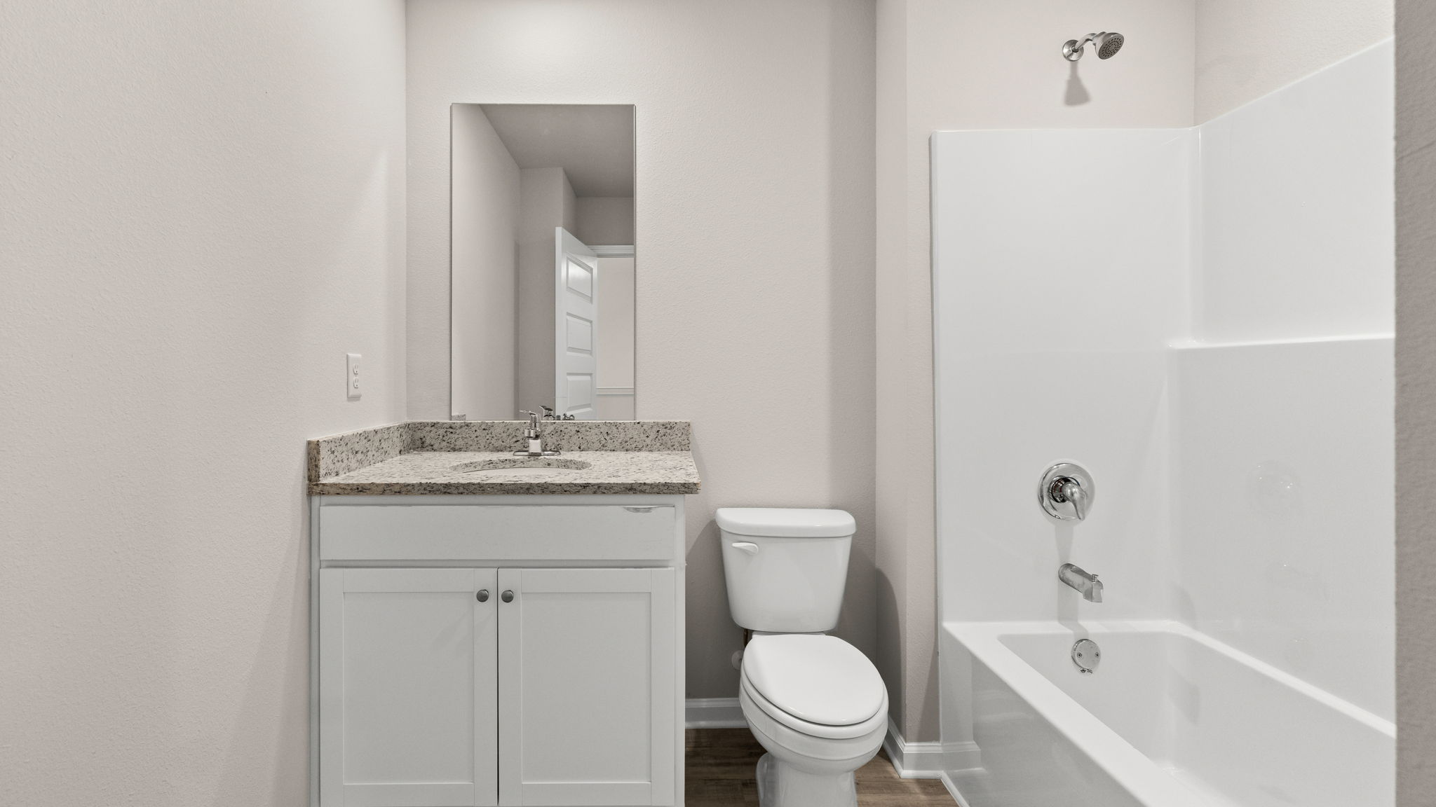 Bathroom with granite countertops and white cabinets and single vanity sinks and toilet and shower.