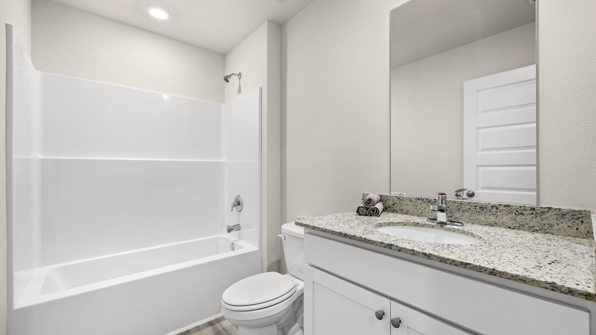 Bathroom with granite countertops and white cabinets and single vanity sinks and toilet and shower.
