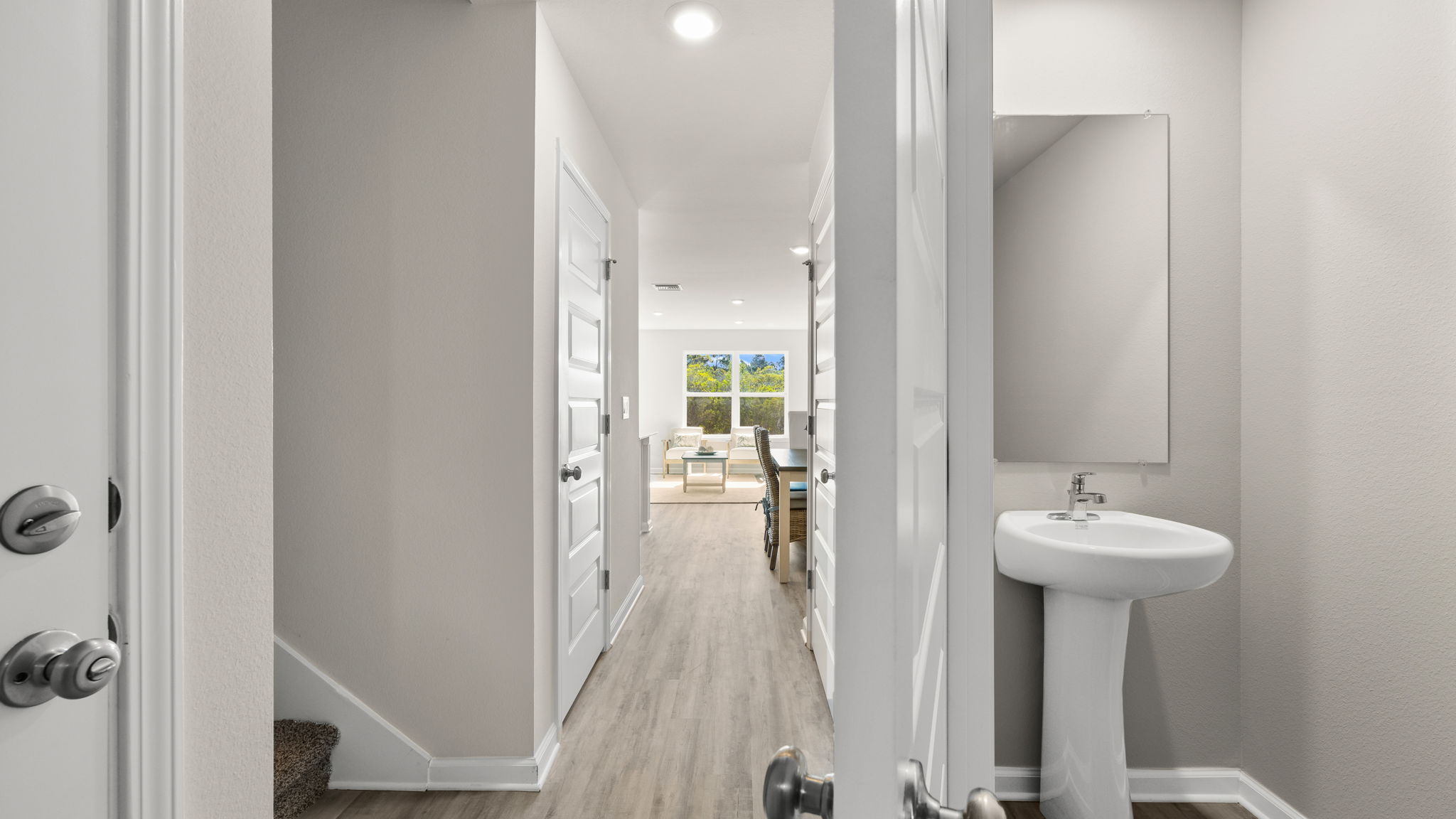 Front entrance hallway with EVP flooring next to garage and half bathroom and stairs.