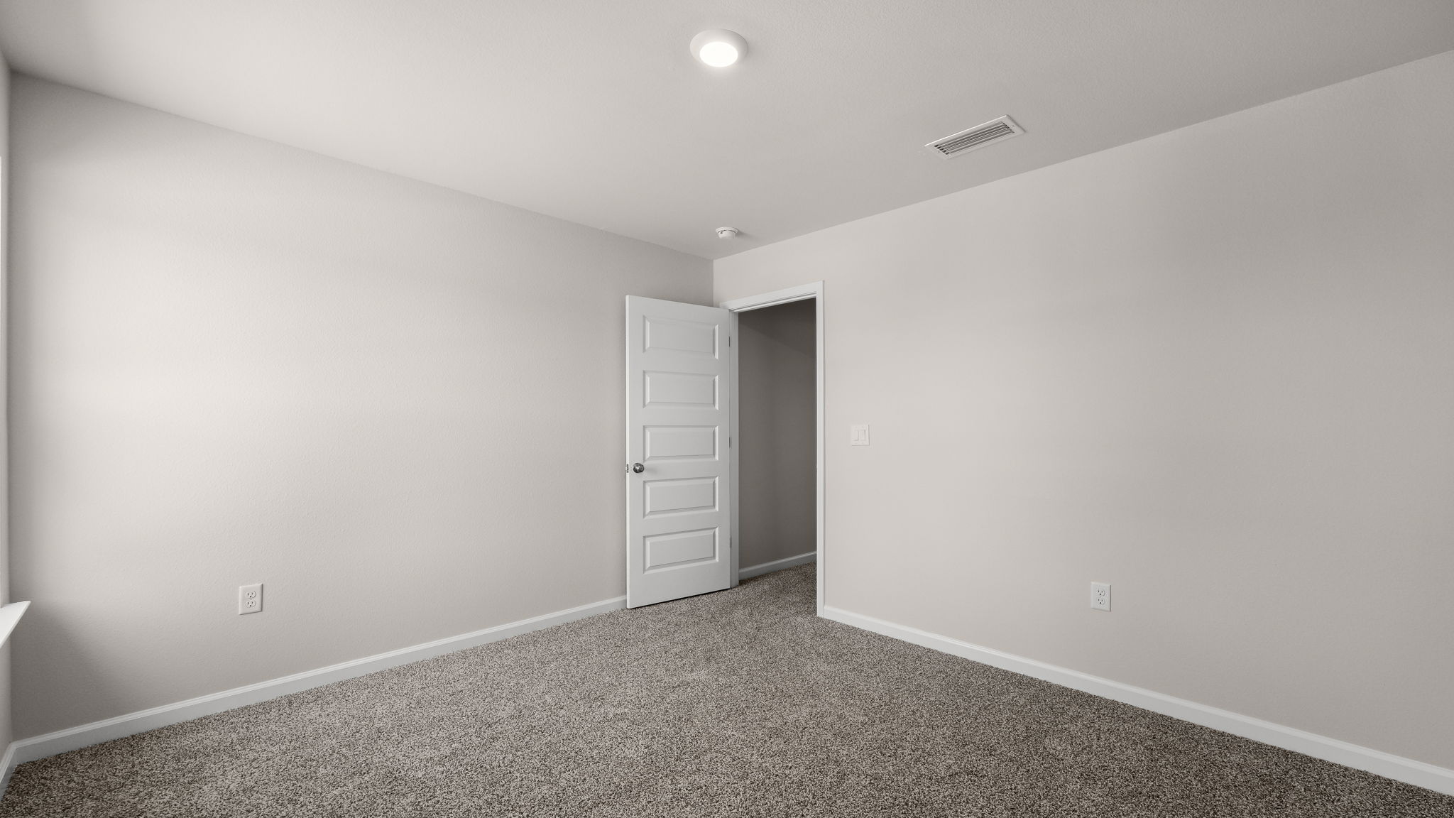 Primary bedroom with carpet floor and hallway entrance.