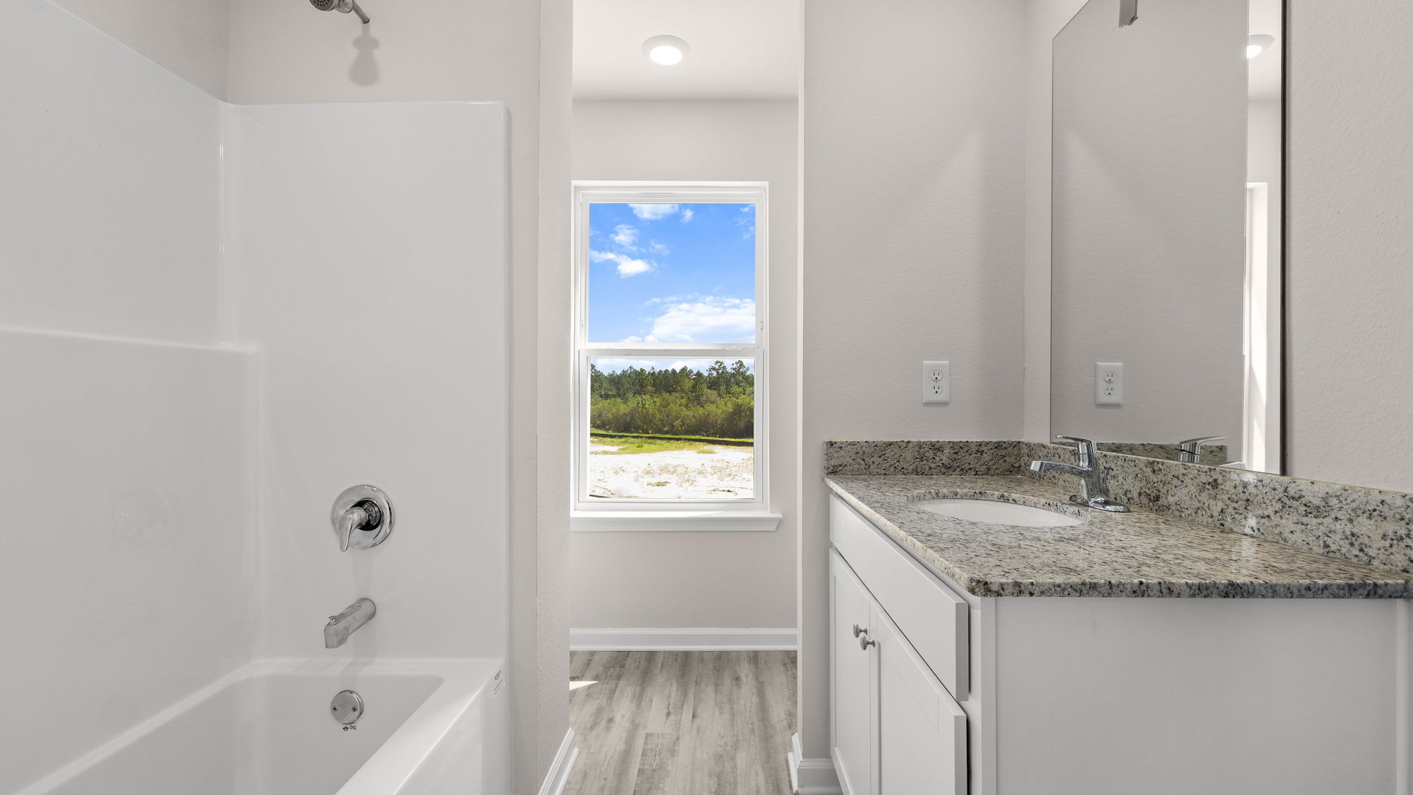 Primary bathroom with granite countertops and white cabinets and single vanity sink and toilet and shower.