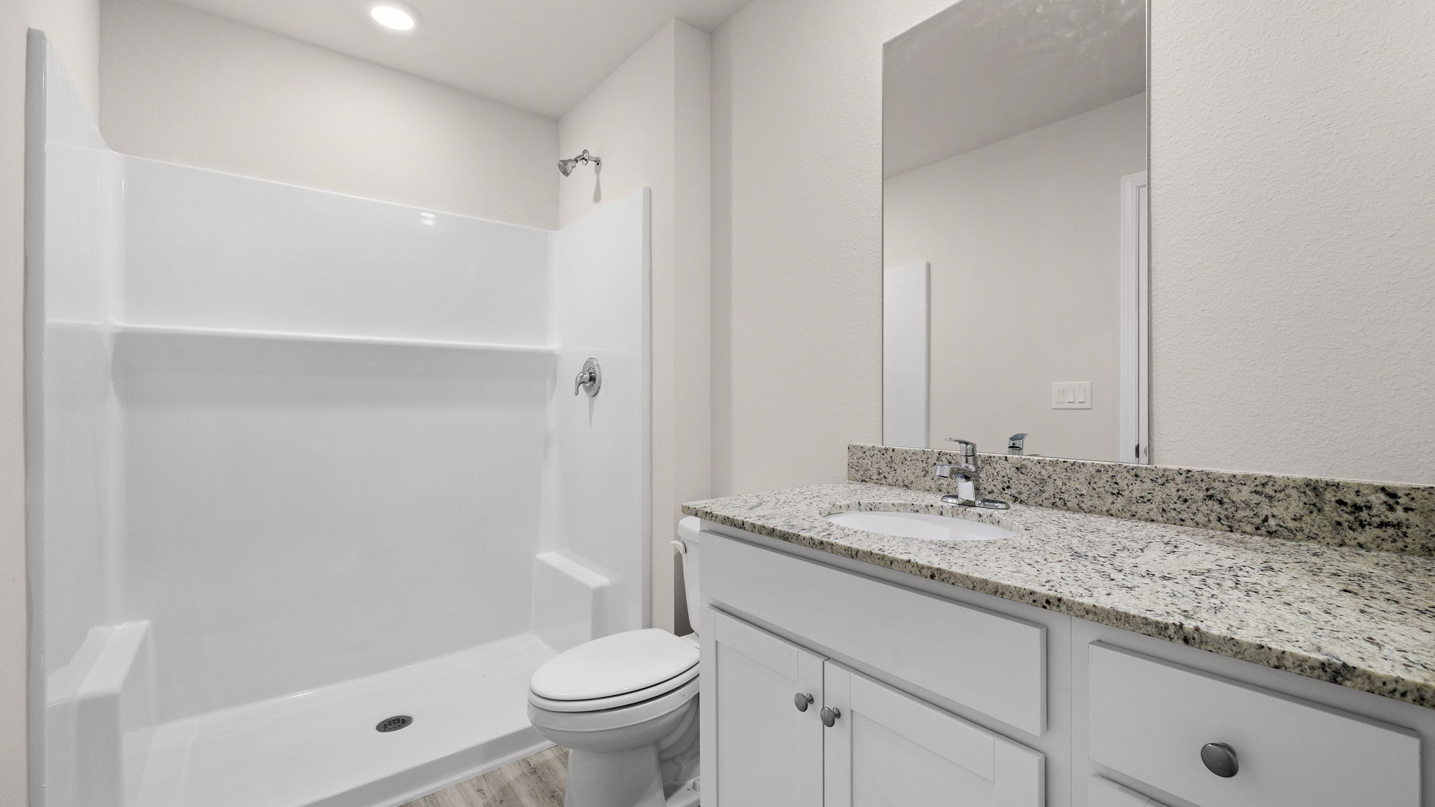 Bathroom with granite countertops and white cabinets and single vanity sinks and toilet and shower.