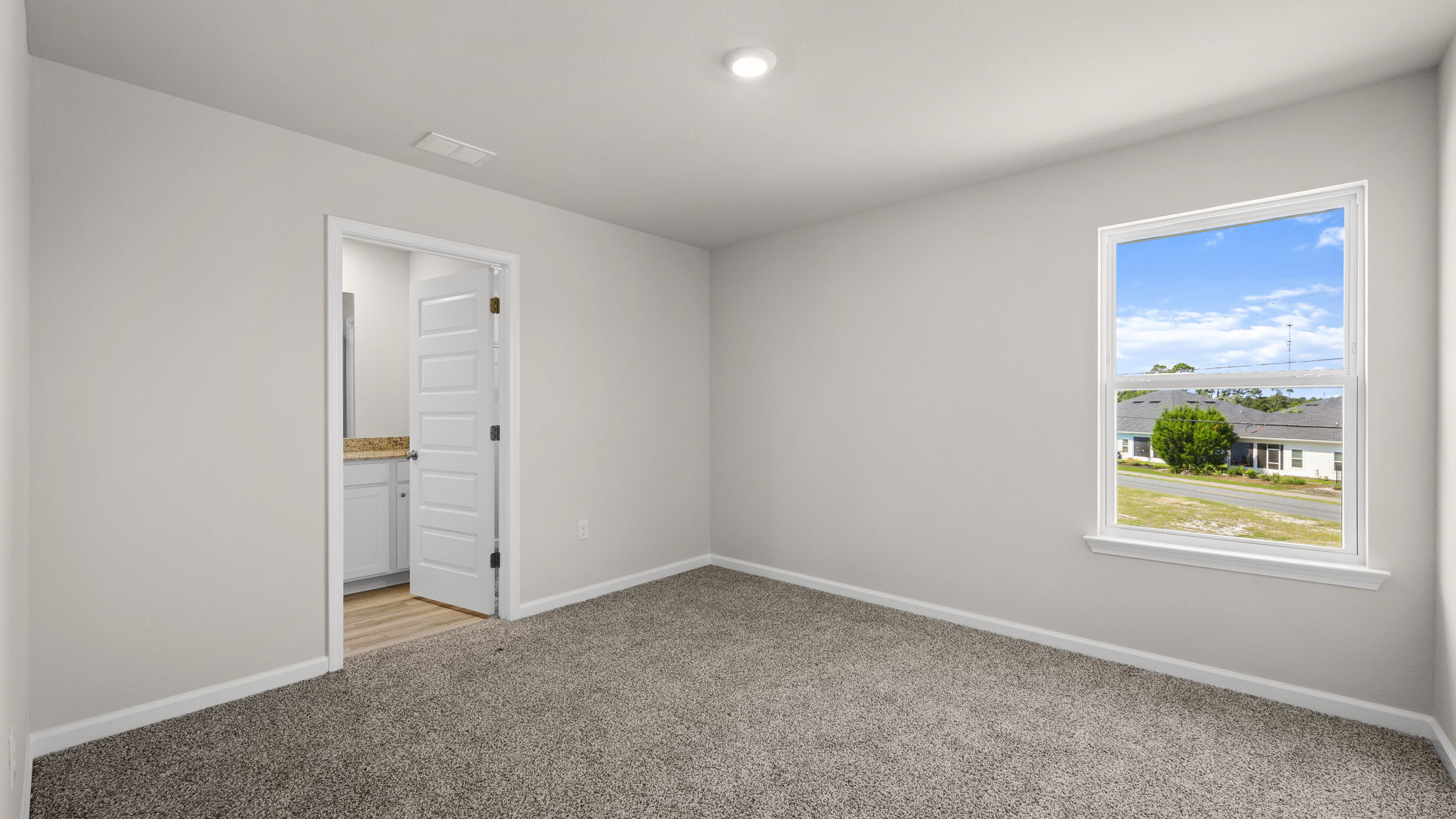 Primary bedroom with carpet floor and bathroom entrance.