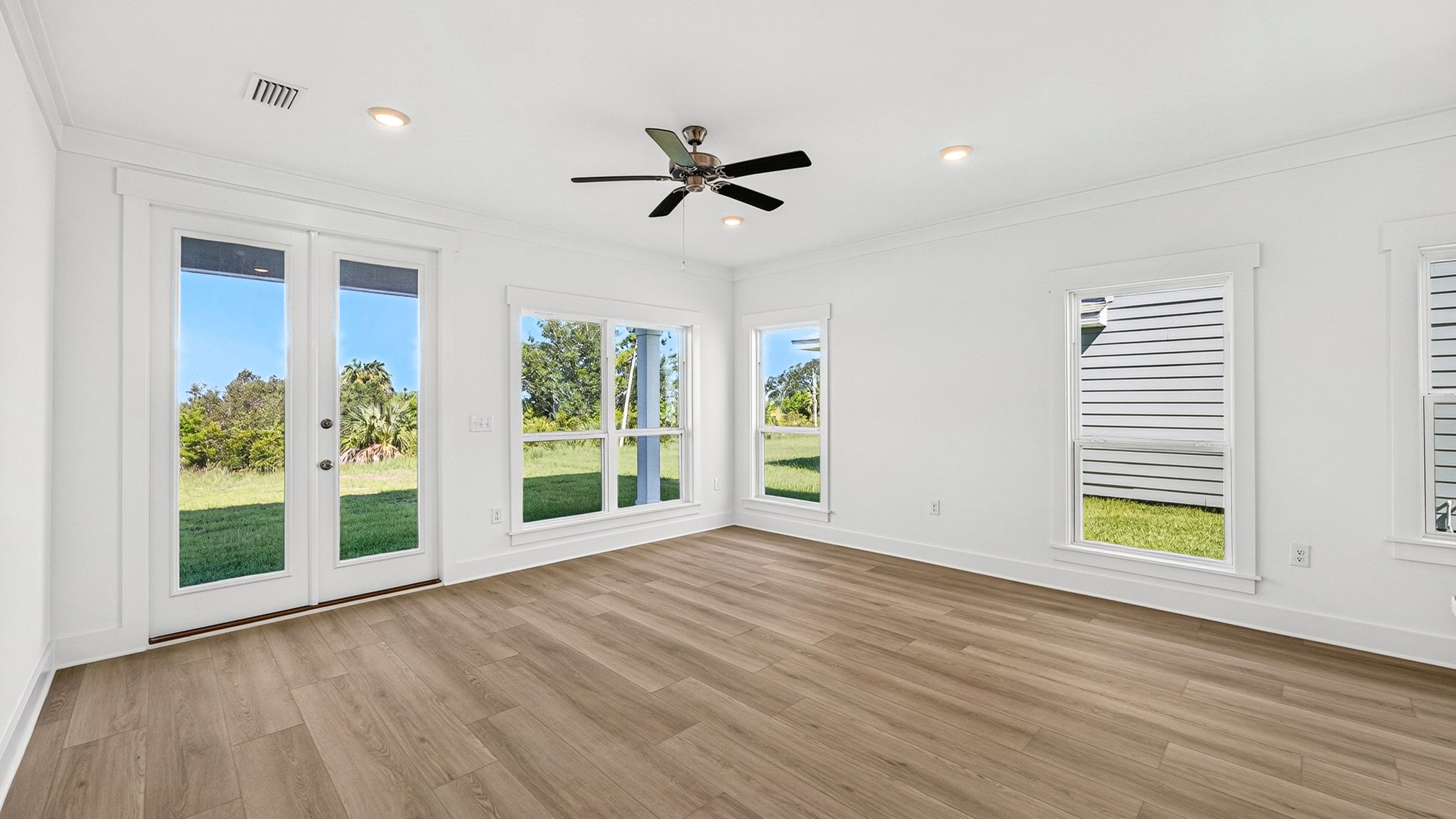 Open living room with EVP flooring and ceiling fan and large windows.