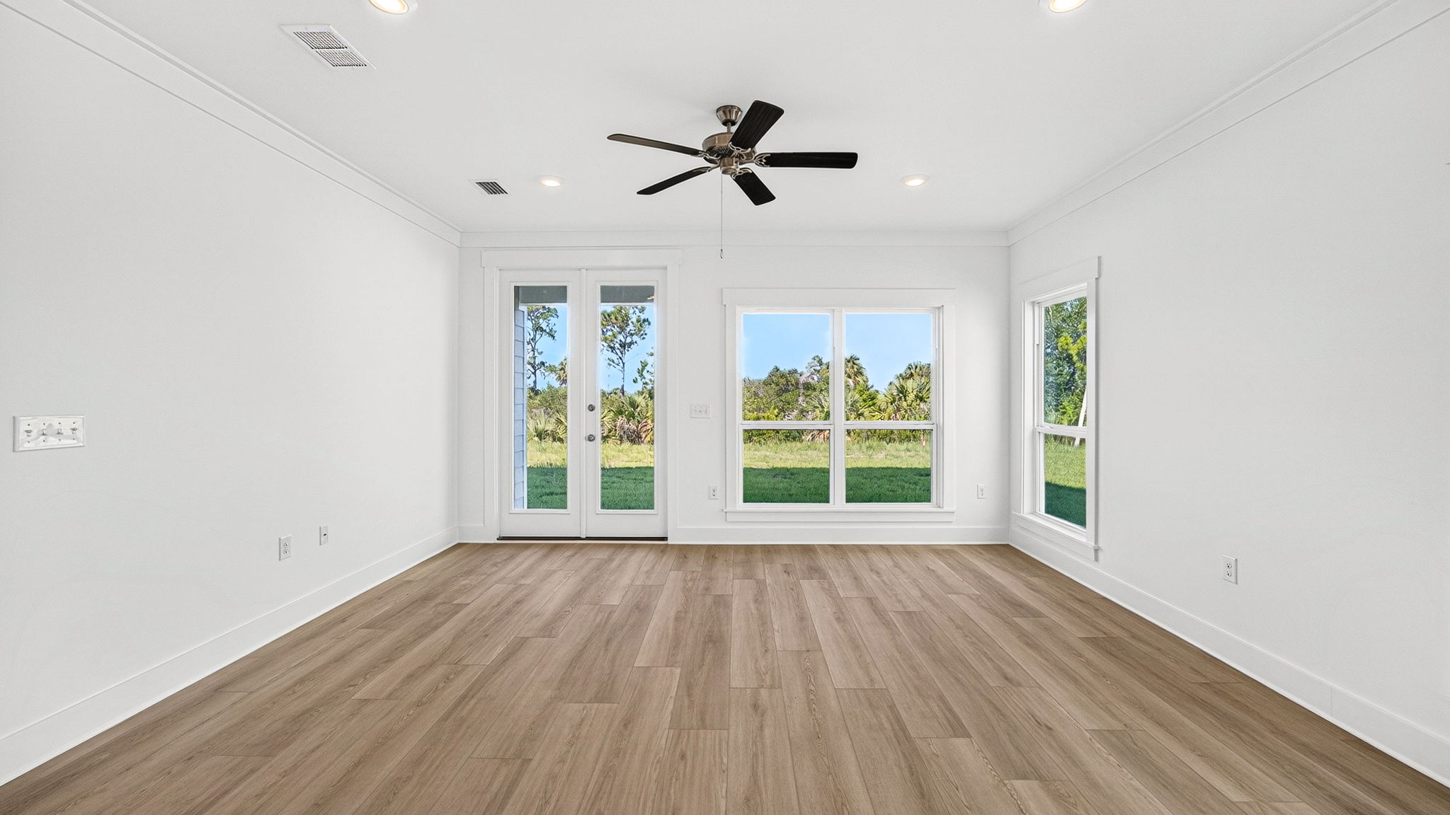 Open living room with EVP flooring and ceiling fan and large windows.
